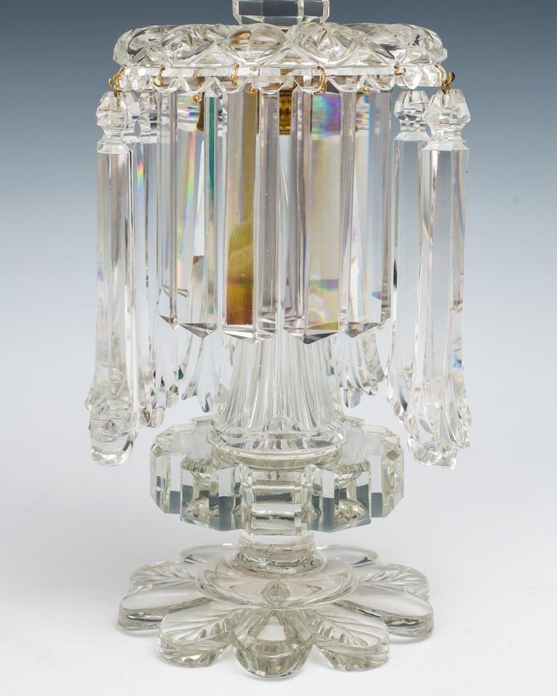 A pair of rare pillar and feather cut William IV lustres hung with very unusual fan end rule drops and a second row of flat cut rule drops, the candle nozzle and stem collar cut with unusual segmented square section.
Measures: Height 31 cm (12