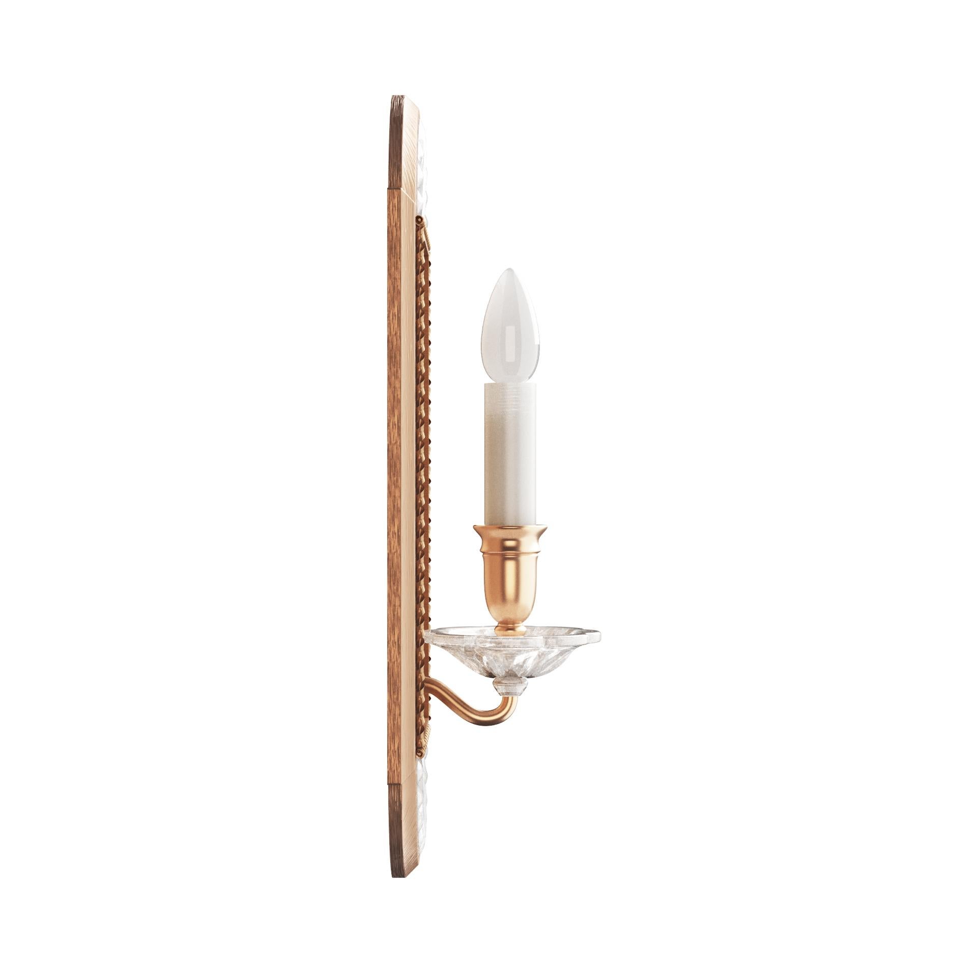A pair of brass single-light sconces with carved rock crystal bobeches and shell motifs. Candle arms emerge from oval shaped backplates with decorative trim. Also available with cylindrical glass covers. Made by David Duncan Studio in New York