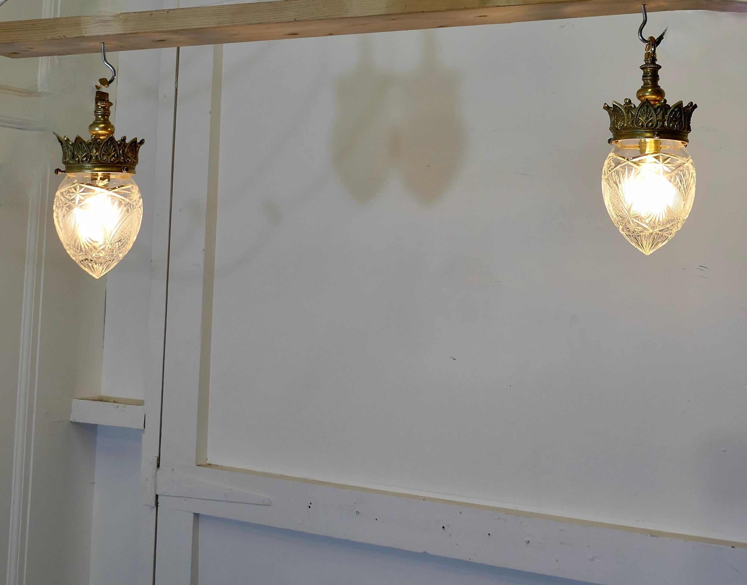  A Pair of Victorian Arts and Crafts Brass Ceiling Lights

The Lights have very decorative brass coronet gallery, they have their original Cut Crystal Shades 

All in working order, these lights will need to be connected to an electrical supply 
The