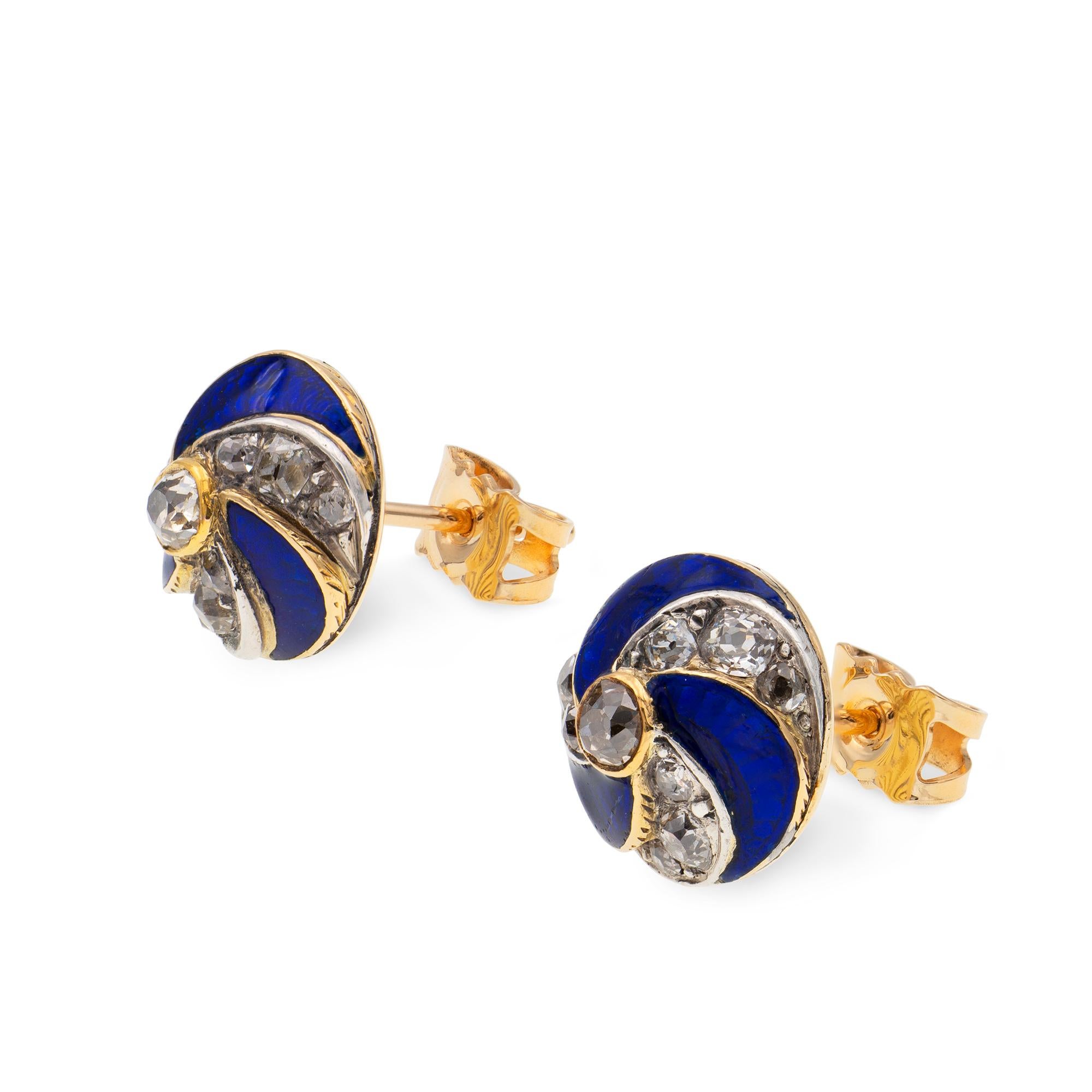 A pair of Victorian blue enamel and diamond stud earrings, each stud centrally set with an old-cut diamond, surrounded by three blue enamelled and three diamond-set sections of spiral design, the diamonds estimated to weigh 1 carat in total, all set