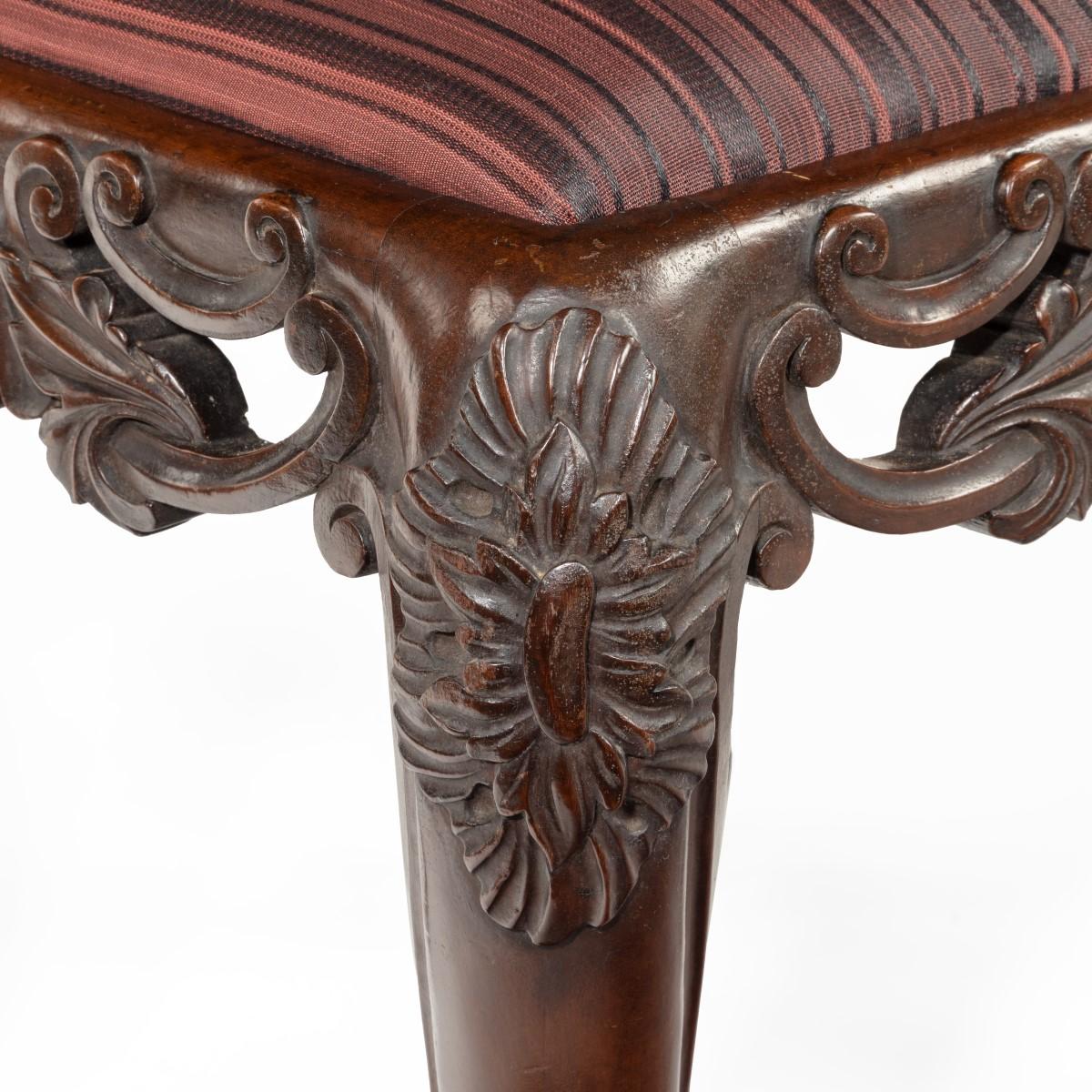 A pair of Victorian carved mahogany stools, each of square form with a pierced frieze and raised on scrolling cabriole legs, the drop-in seats upholstered in woven horsehair. English, circa 1845.