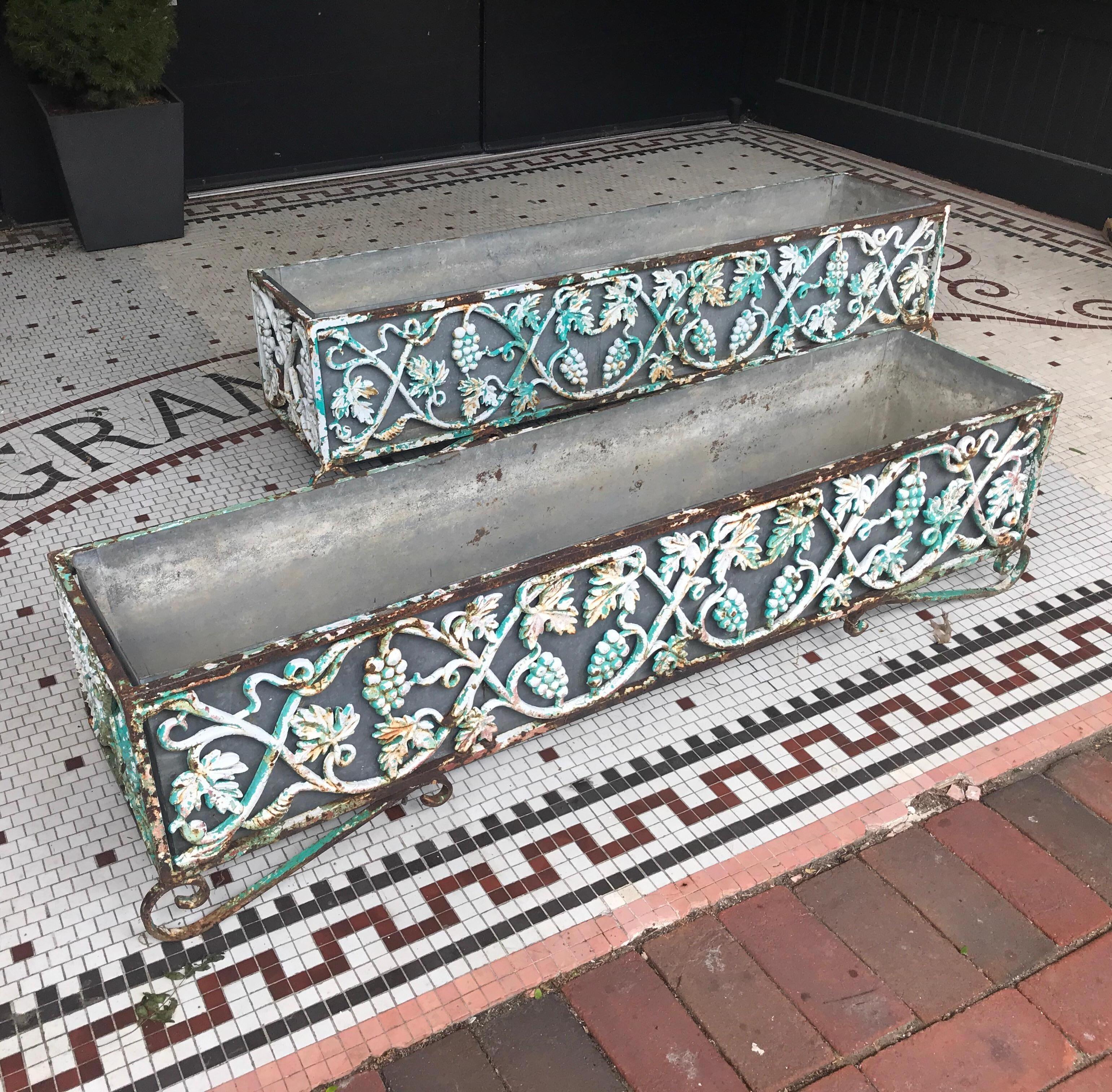 Great pair of early 20th century cast iron planters with galvanized steel liners. The cast iron planters in grape vine and leaf design fitted with galvanized steel liners. Each showing weathered surface and different colors of layered paint.