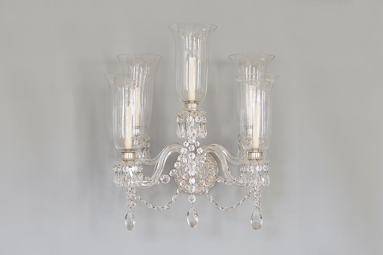A pair of fine Victorian cut glass wall lights, 19th century, each with five light sources, the scrolling arms each fitted with a glass lamp shade. Silver plated fittings wired for electricity.