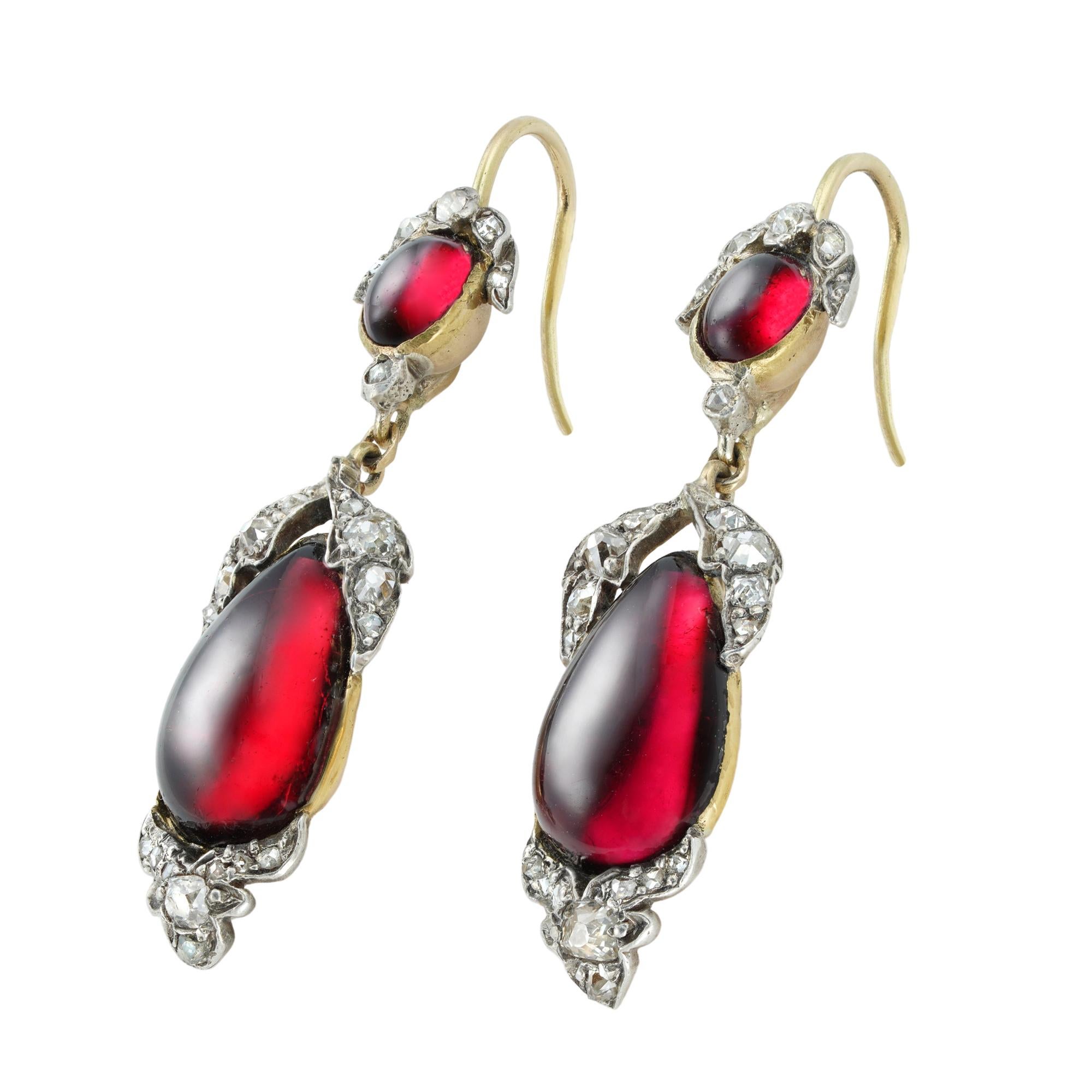 A pair of Victorian garnet and diamond drop earrings, each earring consisted of an oval cabochon garnet with diamond-set leaves above, suspending a pear-shape cabochon garnet with similar foliate diamond-set decorations, all mounted in silver and