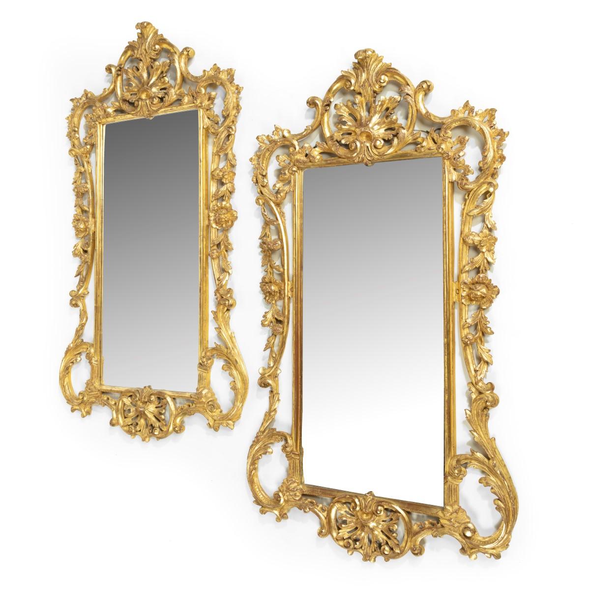 A pair of Victorian giltwood mirrors in the Chippendale style, each with a rectangular plate enclosed within an ornate openwork frame carved with a symmetrical arrangement of C-scrolls, acanthus leaves and rocailles.