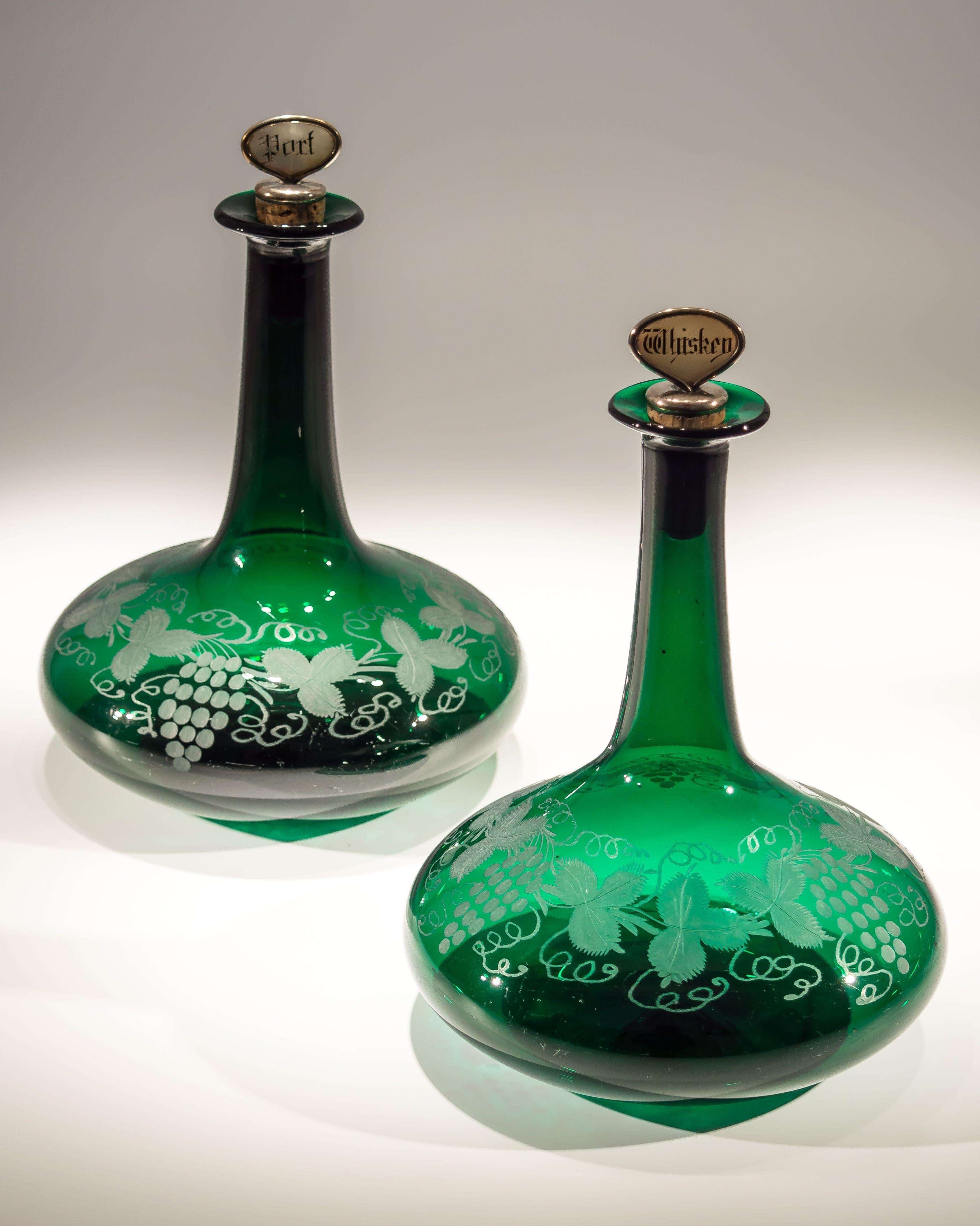 A pair of Victorian green mells decanters engraved fruiting vine with cork stoppers labelled Port and Whiskey.

England, 1880.