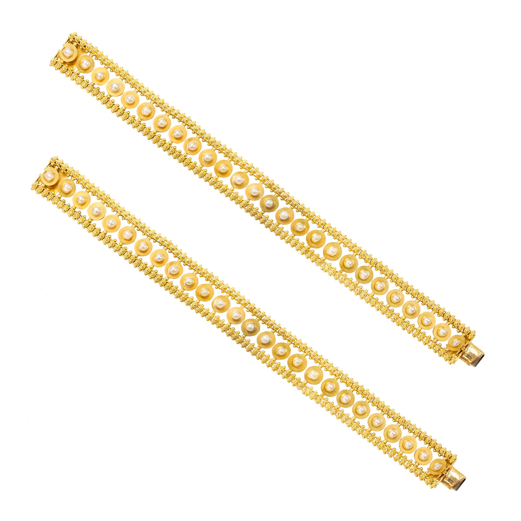 A pair of Victorian half pearl gold bracelets, each bracelet consisting of twenty six gold discs each set with half pearl to the centre and suspended between two cannatile chains, all fire gilded to a concealed snap clasp, circa 1890, measuring