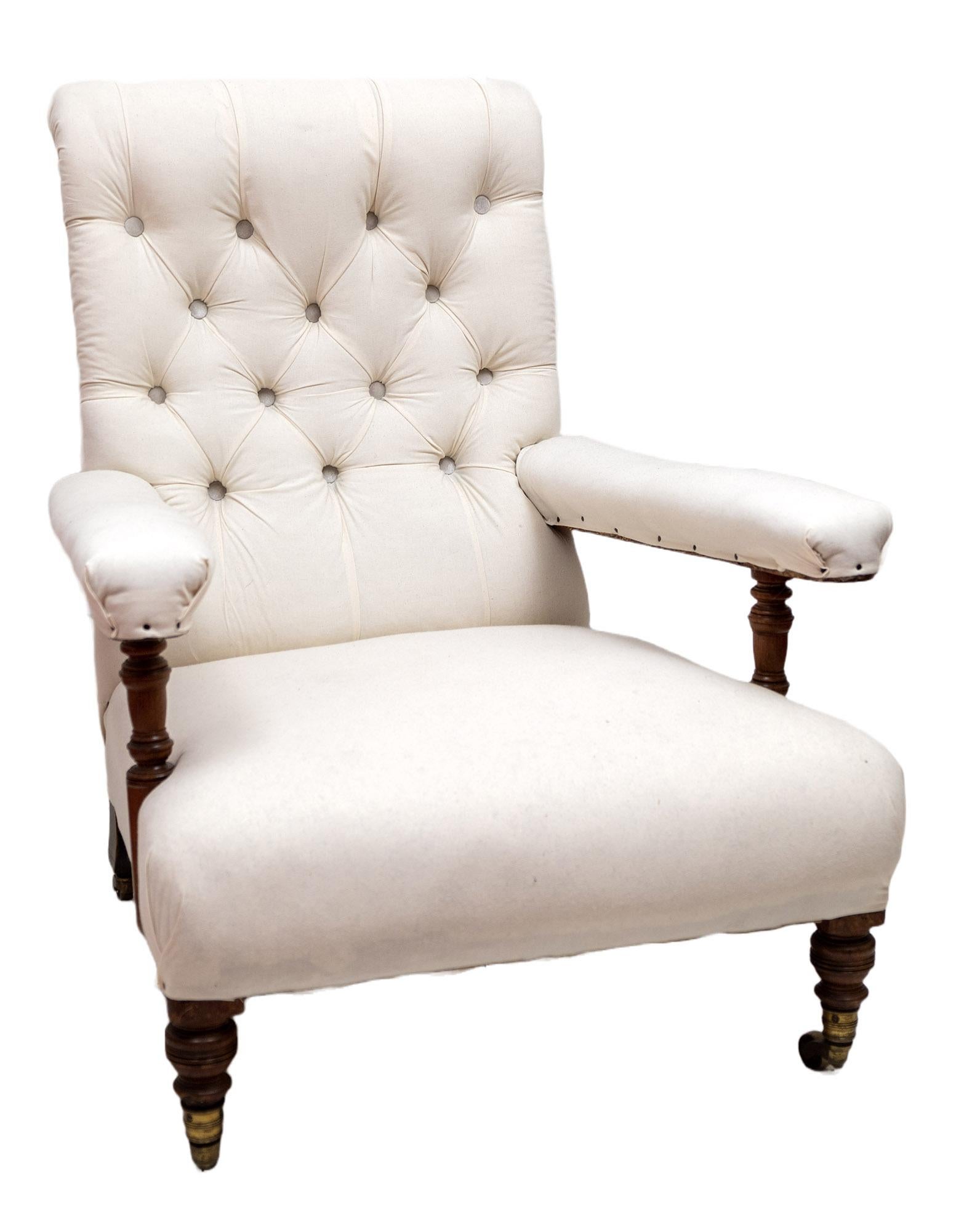 Each with turned walnut legs, and turned walnut supports under the armrest, upholstered in white calico with deep button-back detailing and horsehair stuffing. The brass castors stamped 'HOWARD AND SONS', and the back legs stamped 'HOWARD AND SONS'