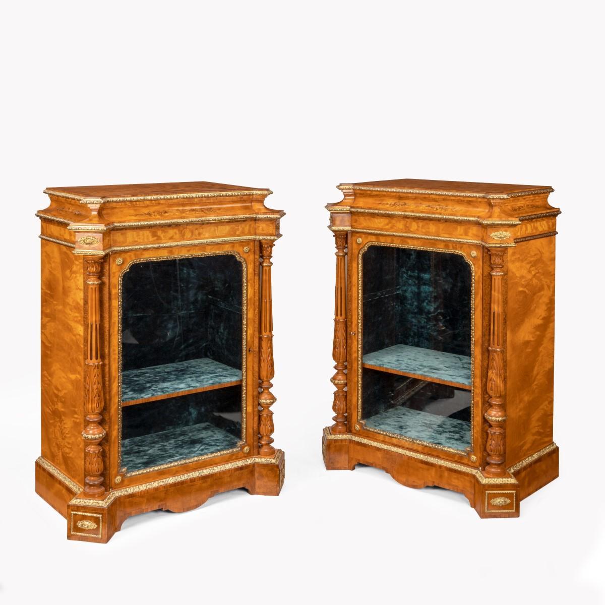 A pair of Victorian satinwood display cabinets attributed to Holland and Sons, each of stepped, rectangular form with protruding square-cut corners holding turned stop-fluted and acanthus-carved pillars, with a central glazed door opening left- and