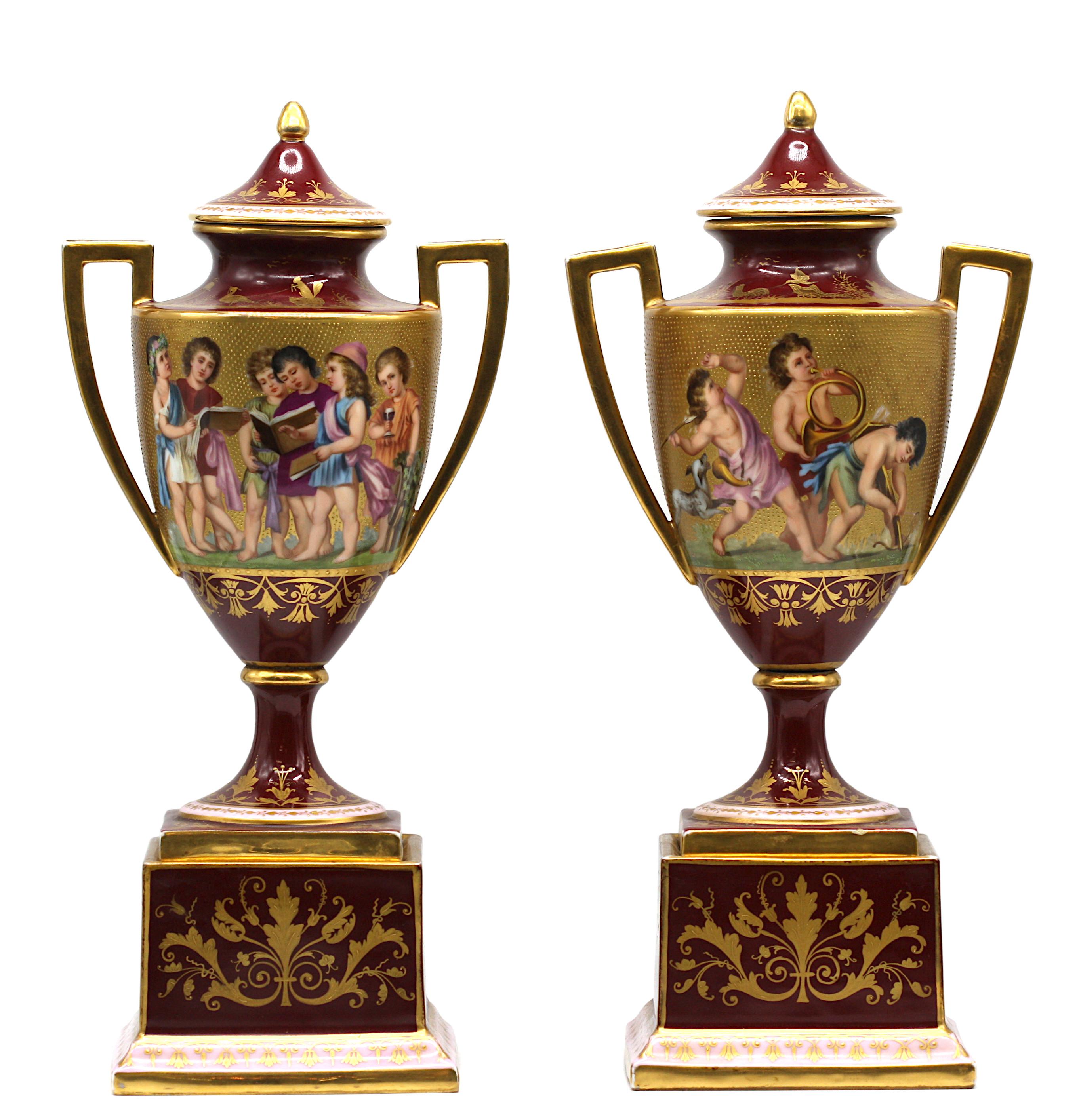 A pair of Vienna style Two-Handled Vases and Covers on Bases, circa 1890
of cylindrical form affixed with two scroll handles, painted with classical scenes, the elaborate body composed of multi-coloured enamels and gilt, reserved on a dark-red