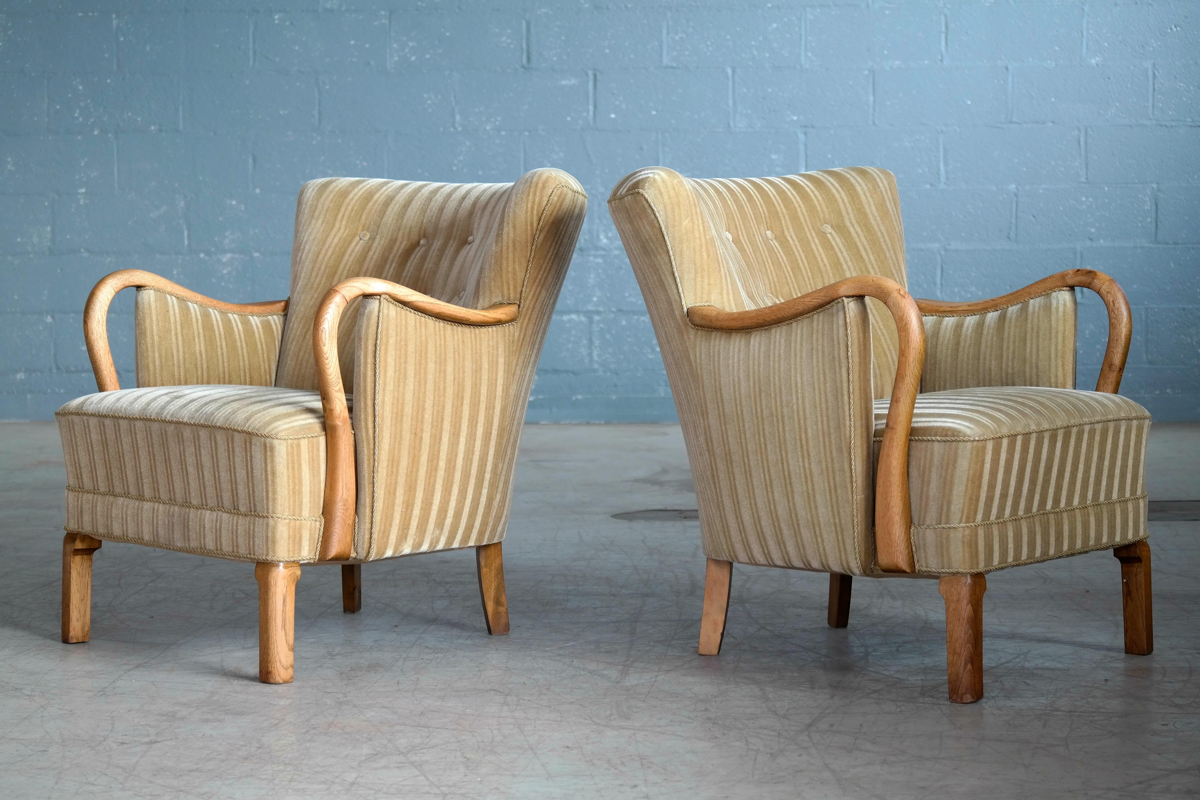 Sublime pair of lounge chairs made by Slagelse Mobelvaerk of Denmark in the 1940s with the design attributed to Viggo Boesen. These elegant chairs display the same leg design seen on other of Boesen chairs and the wooden armrests in solid oak are