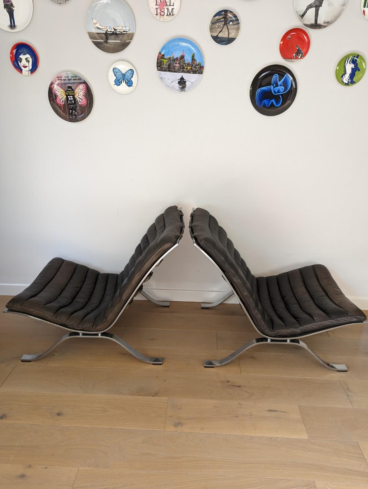 A beautiful pair of Arne Norrell 'Ari' chairs for Mobel AB in black leather.

The low slung chrome frame is in fantastic condition with only minimal age related wear. The frame has leather straps that support the leather seat cushion which clips