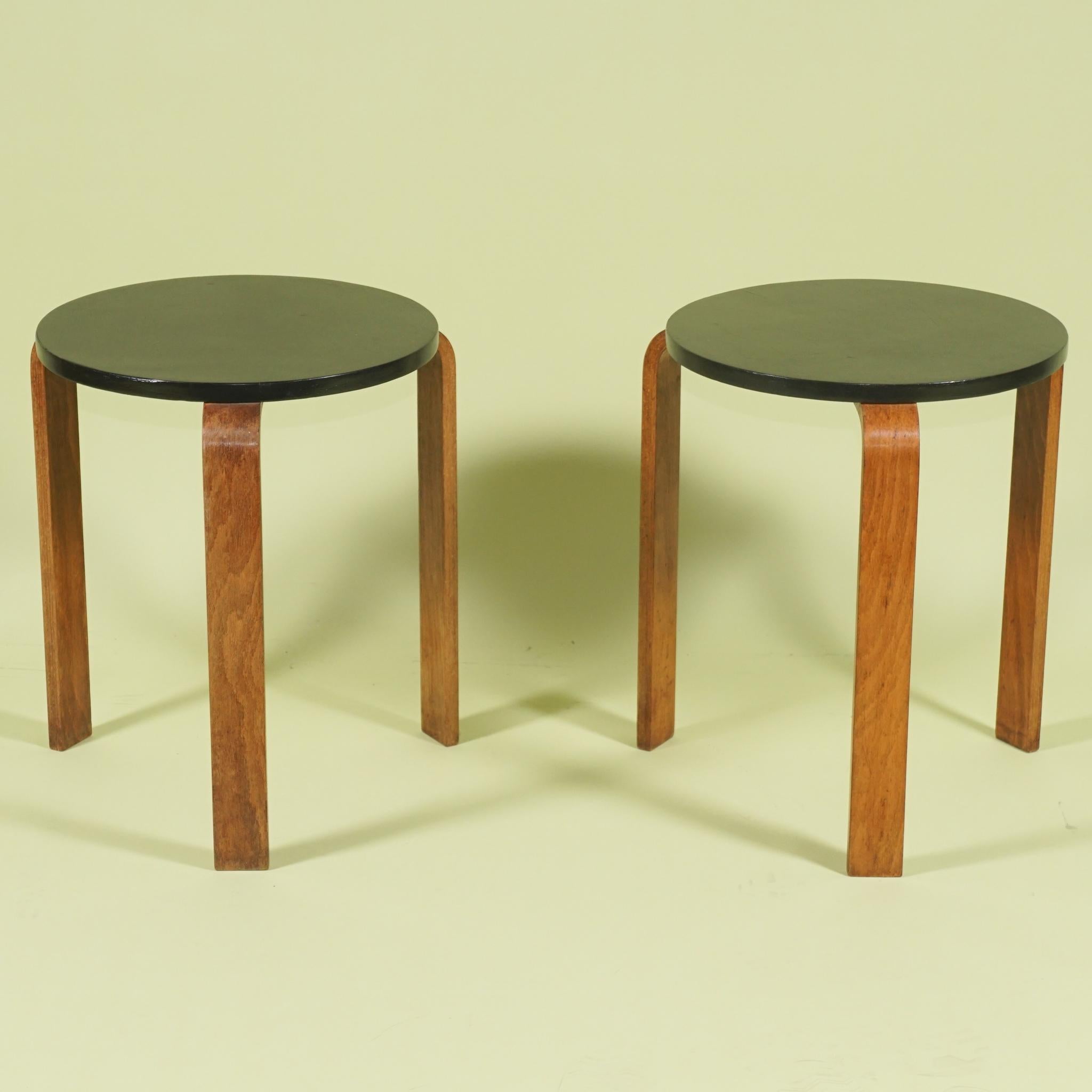Cette paire de tabourets bas ou tables vintage à trois pieds du designer Alvar Aalto a été présentée pour la première fois dans les années 1930. Toutes deux fabriquées vers 1955 et ayant manifestement toujours vécu leur vie ensemble, elles sont