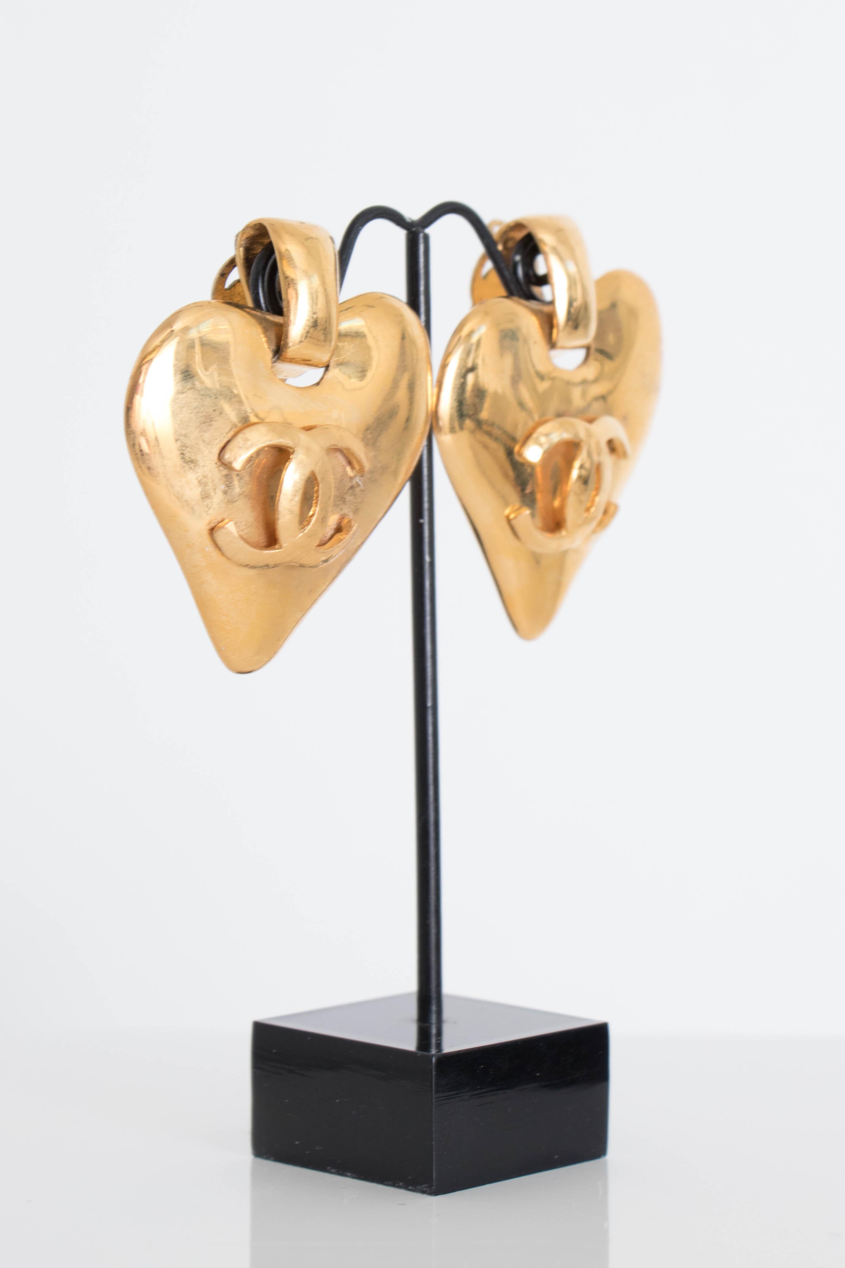A pair of 1993 Chanel gold toned heart shaped pendant clip-on earrings with a Chanel double 'C' logo in the centre front.

The earrings are stamped: Chanel, 93, P, Made in France

The earrings measure:
Length: 5 cm
Width: 4.5 cm