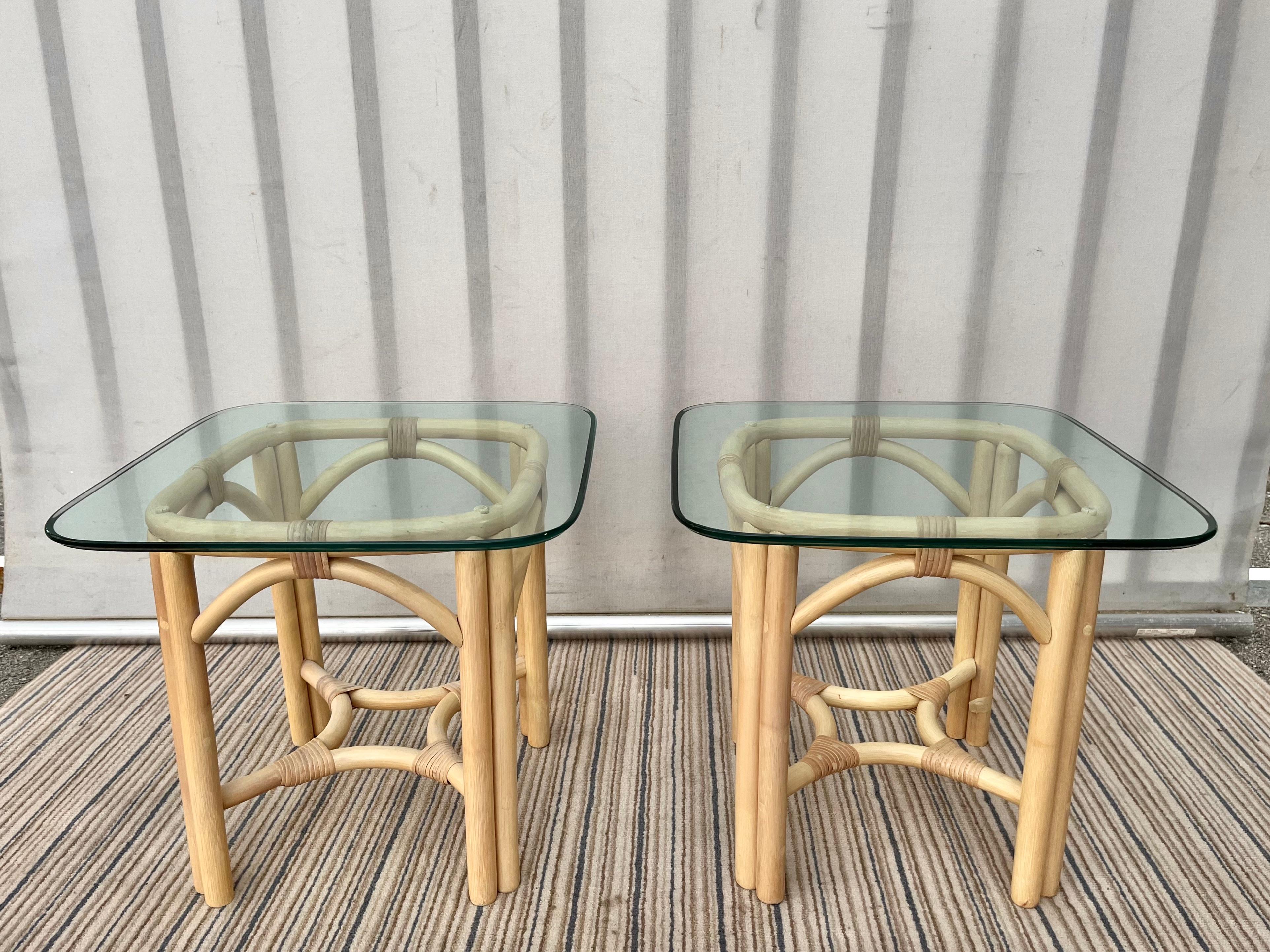 Paire de tables d'appoint en rotin de style côtier Palm Beach Vintage dans le style McGuire. Vers 1980.
Il présente de belles lignes incurvées et un plateau amovible en verre biseauté aux angles arrondis. 
En excellent état, presque neuf, avec de