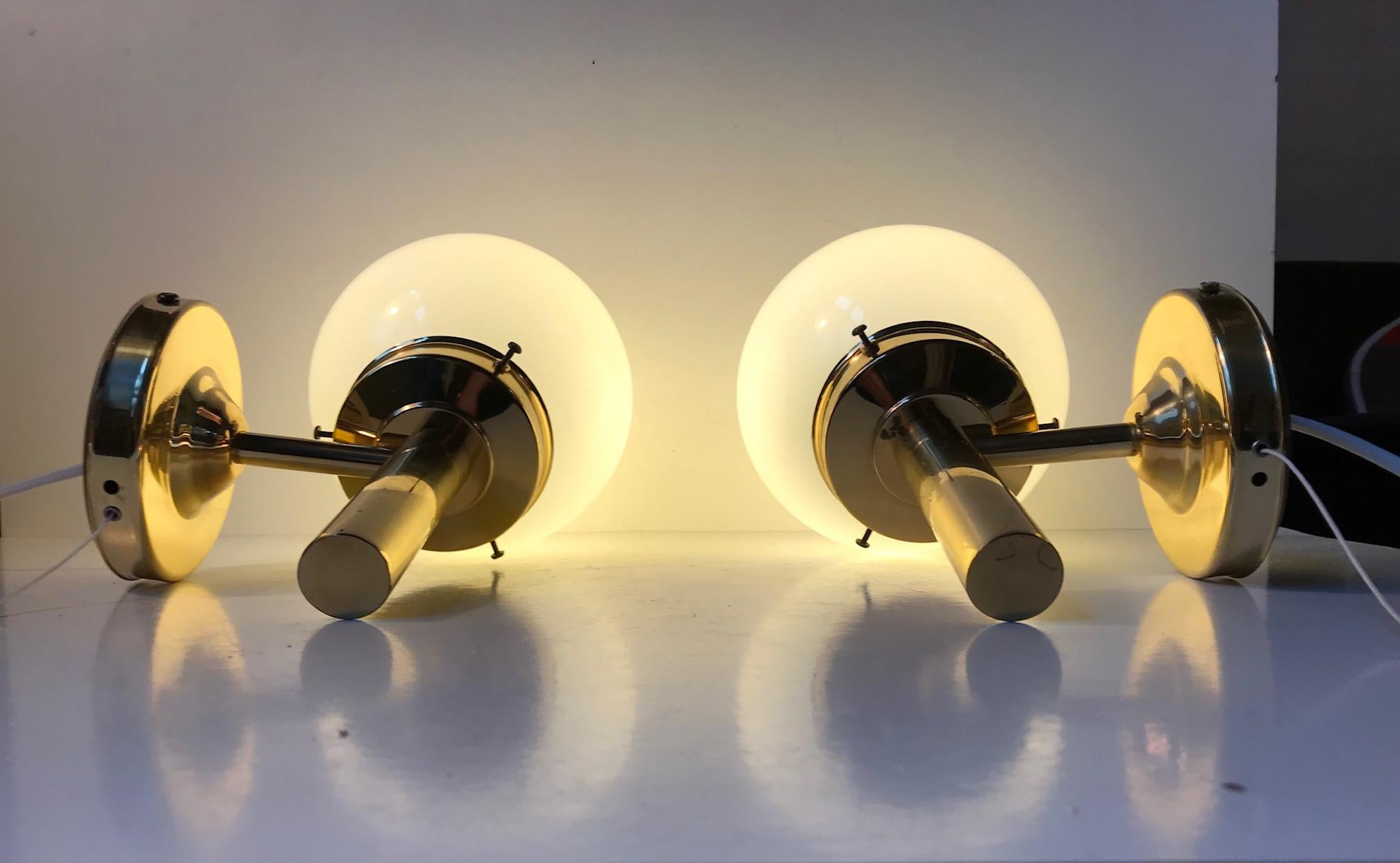 - A pair of maritime sconces
- Made in brass with ball-shaped opaline glass shades
- Manufactured and designed by ABO Metalkunst
- Produced in Randers, Denmark during the 1970s
- In a style reminiscent of Hans-Agne Jakobsson.