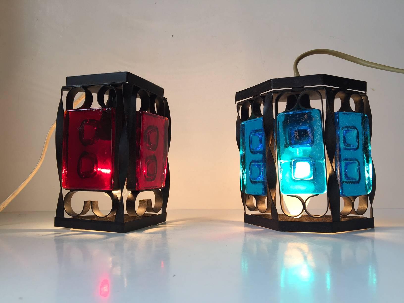 A set of Danish black iron and colored glass sconces. Manufactured and designed in the 1970s as a collaboration between Dantofte and Holmegaard. Measurements: H 16/14 cm (6.2/5.8 inch), W 12/13 (4.8/5.2 inch). Similar to designs by Claus Bolby and