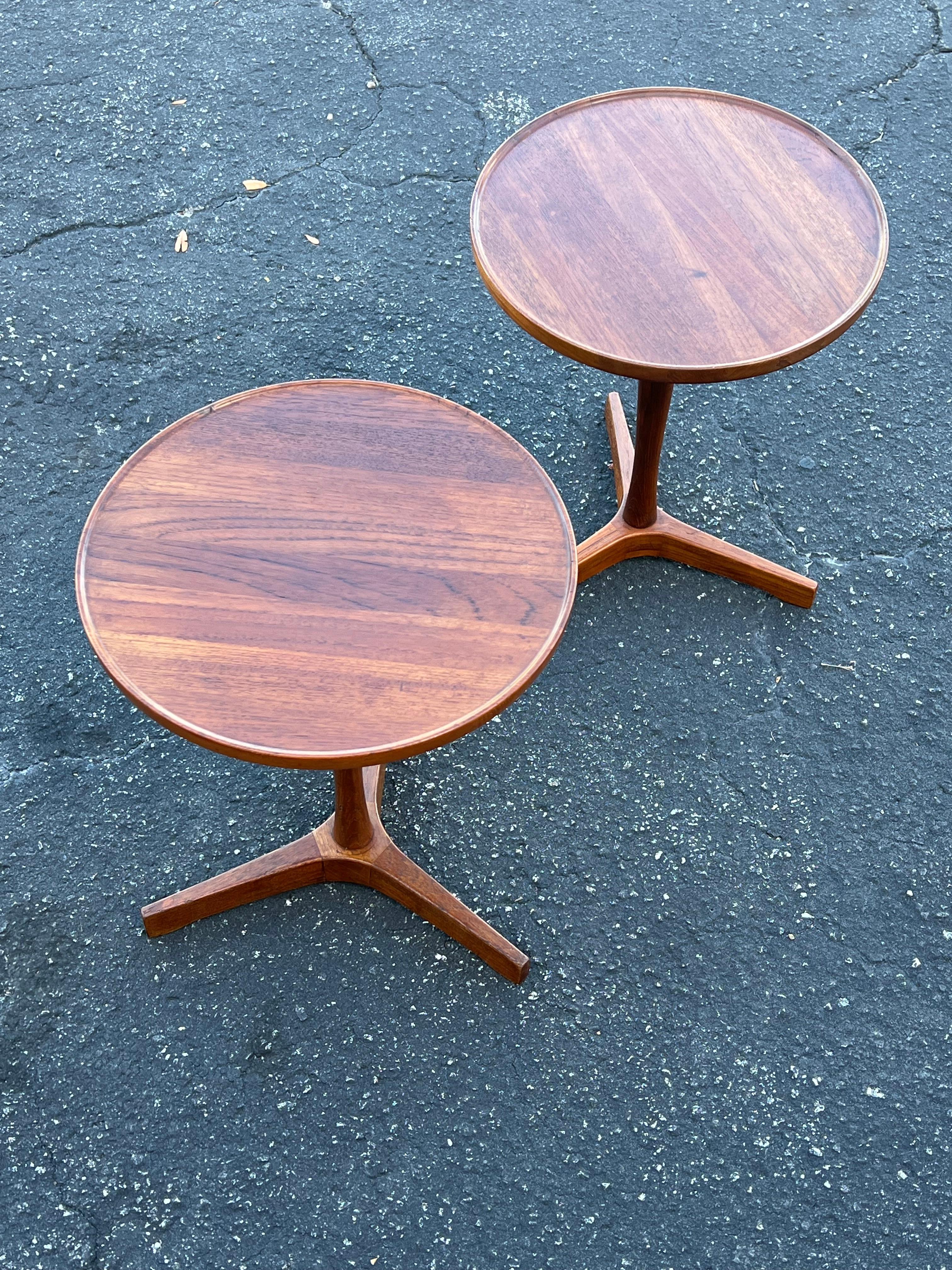 A pair of classic Danish side tables with three legs by Hans Andersen. Round top in solid teak wood.  Nice patina and very good original condition.