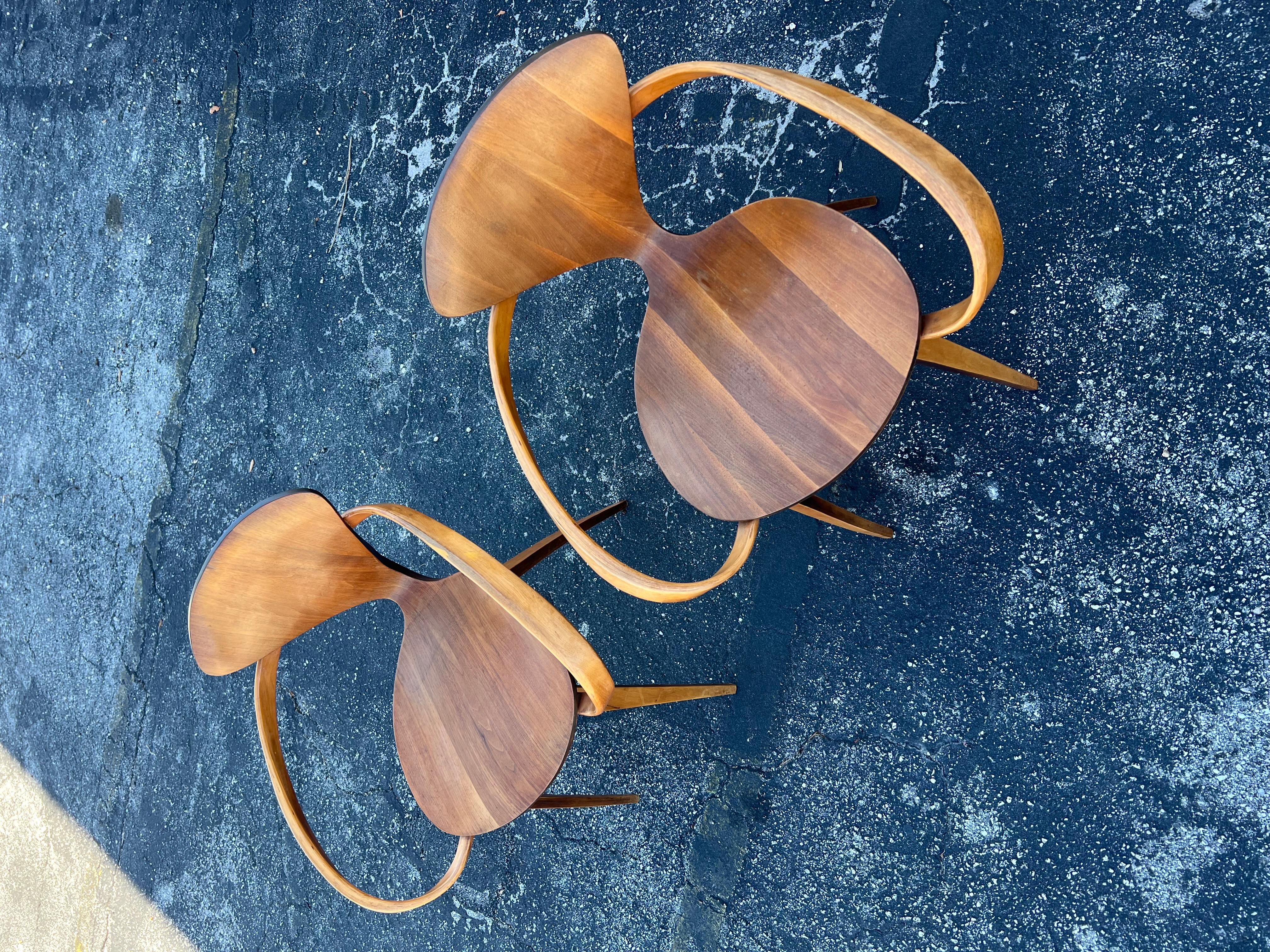 A pair of classic, vintage 1 st edition Cherner chairs with arms. Walnut with nice patina. Both chairs signed with labels-designed by Norman Cherner/Plycraft.