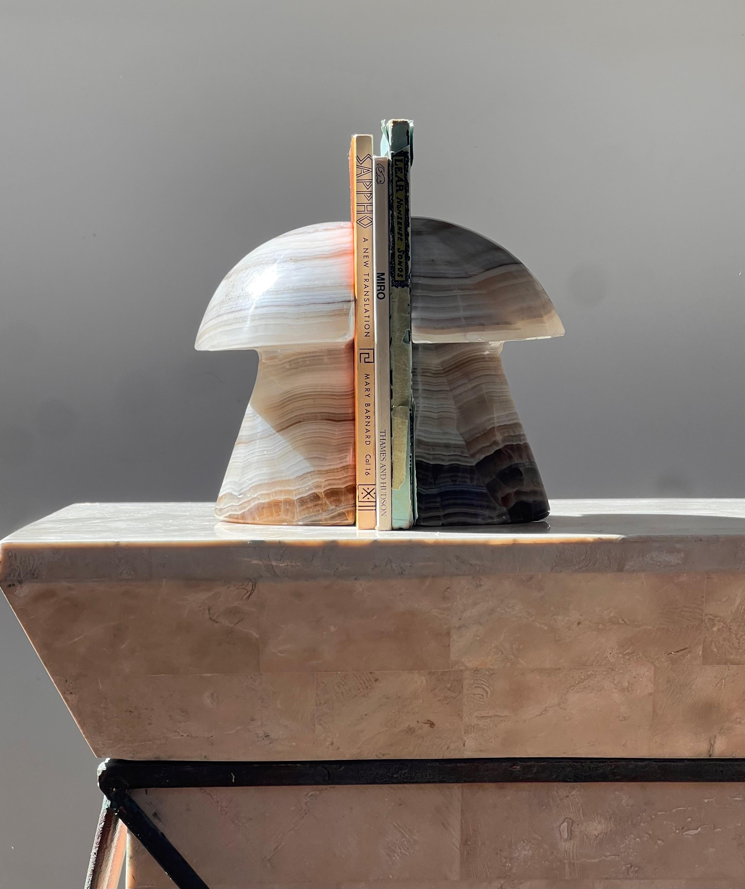 A pair of mid century modern hand-carved onyx mushroom bookends, circa 1970. These psychedelic sculptural bookends truly showcase the exquisite nature of this incredible raw stone, flaunting ombré layers of ivory, chocolate, espresso, and gris. An