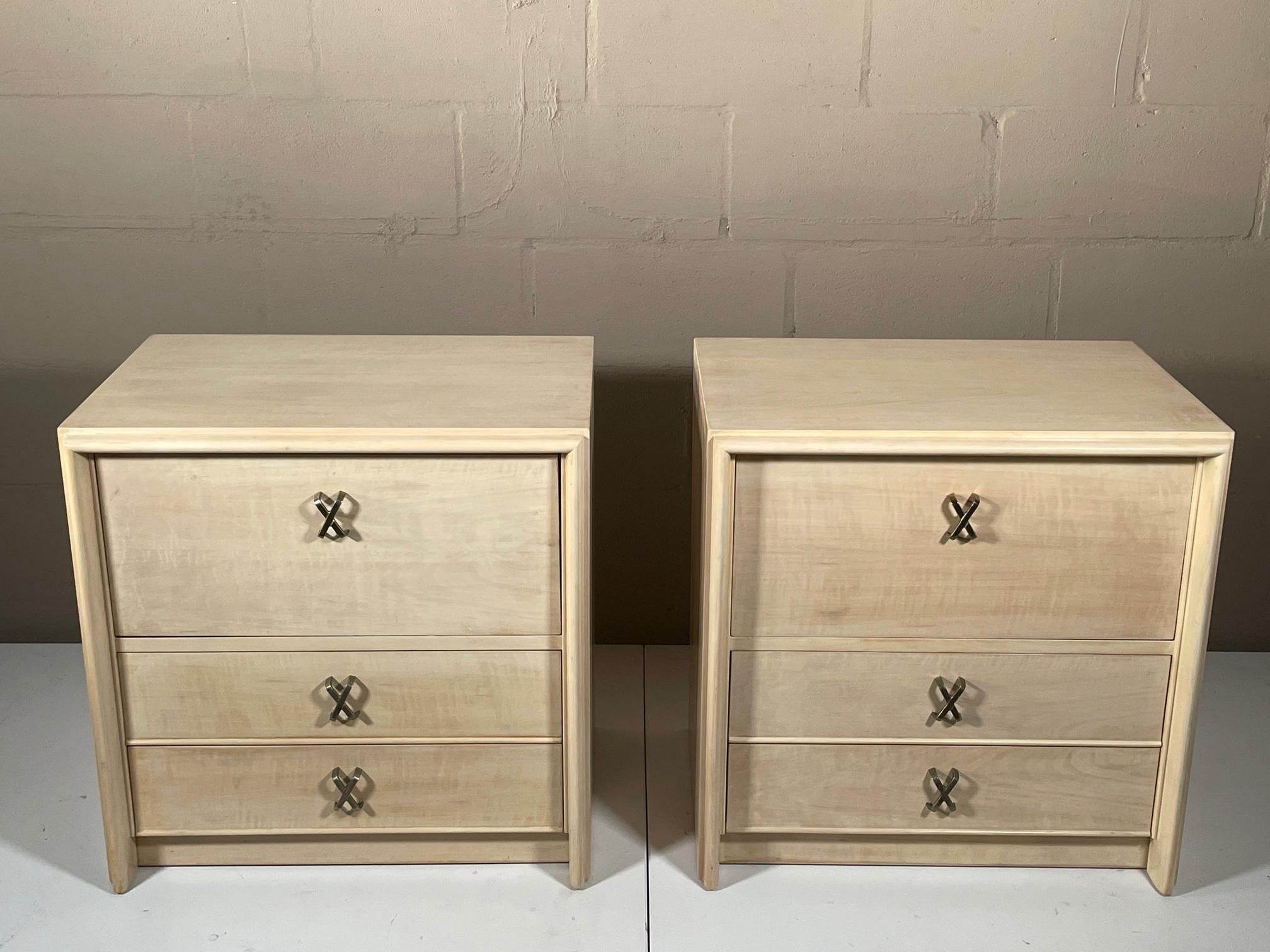 A pair of Paul Frankl nightstands for Johnson Furniture Co, circa 1950s. Brass X-shaped handles, drop down top drawer with two drawers underneath. Custom ivory-white wash finish.