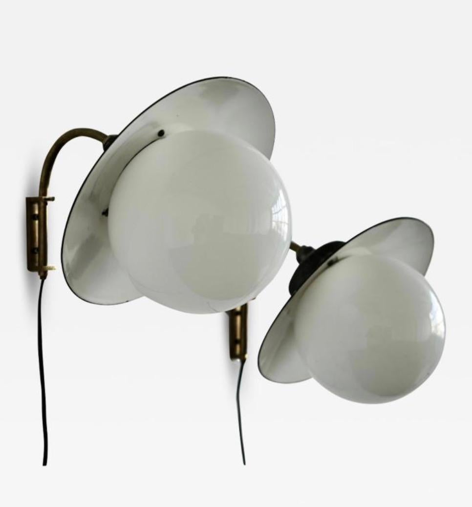 A pair of  indoor/outdoor wall lights designed by Paavo Tynell for Taito Oy, Model 2521-53. Finland Circa 1950th. Painted metal shade with opaline glass globe shade. Marked by manufacturer.
Diam 12″ ; Depth 14″; H 12″.
Rewiring available upon