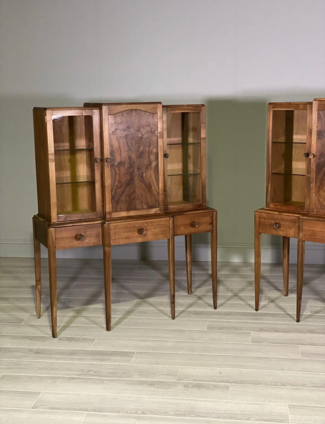 A matching pair of figured walnut cabinets by Arthur Reynolds of Ludlow dating to the 1930’s. Each cabinet consists of two glazed side cupboards both with two internal glass shelves, with the main centre cupboard having two internal wood shelves
