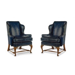 A pair of walnut Georgian style leather wing armchairs