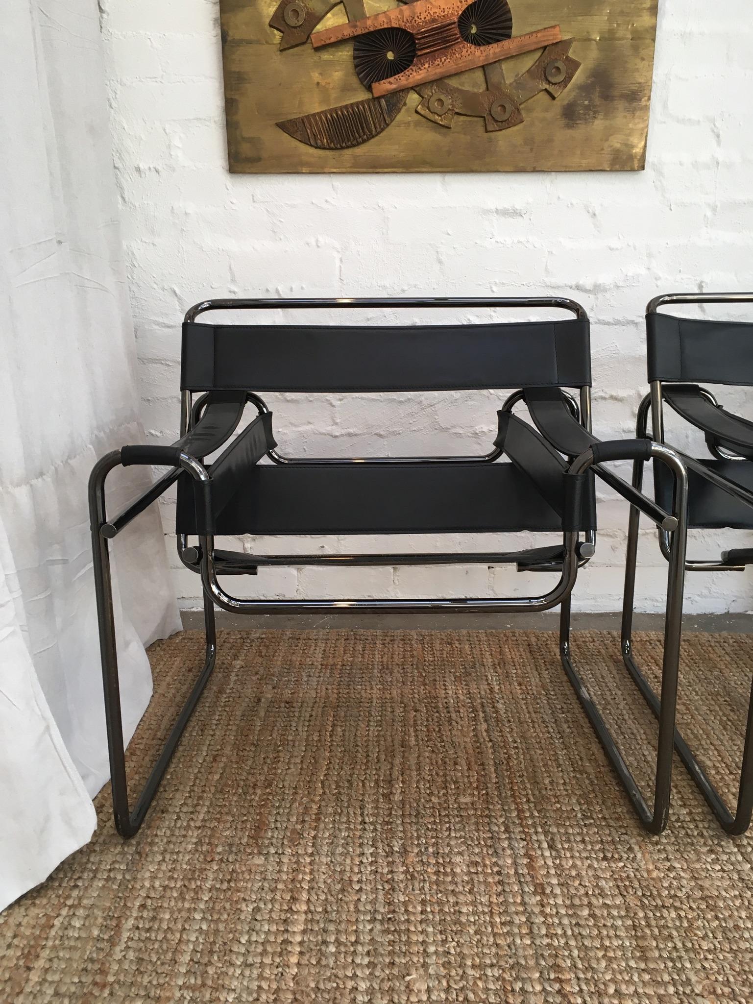 A pair of Classic Wassily chairs, with a truly lovely twist - black anodised frames. Deliciously worn leather. Closed tube ends show these were a quality production. Purchased pre 1985. Sticker to underside of seat, 'Made in Italy'. 

The rubbing