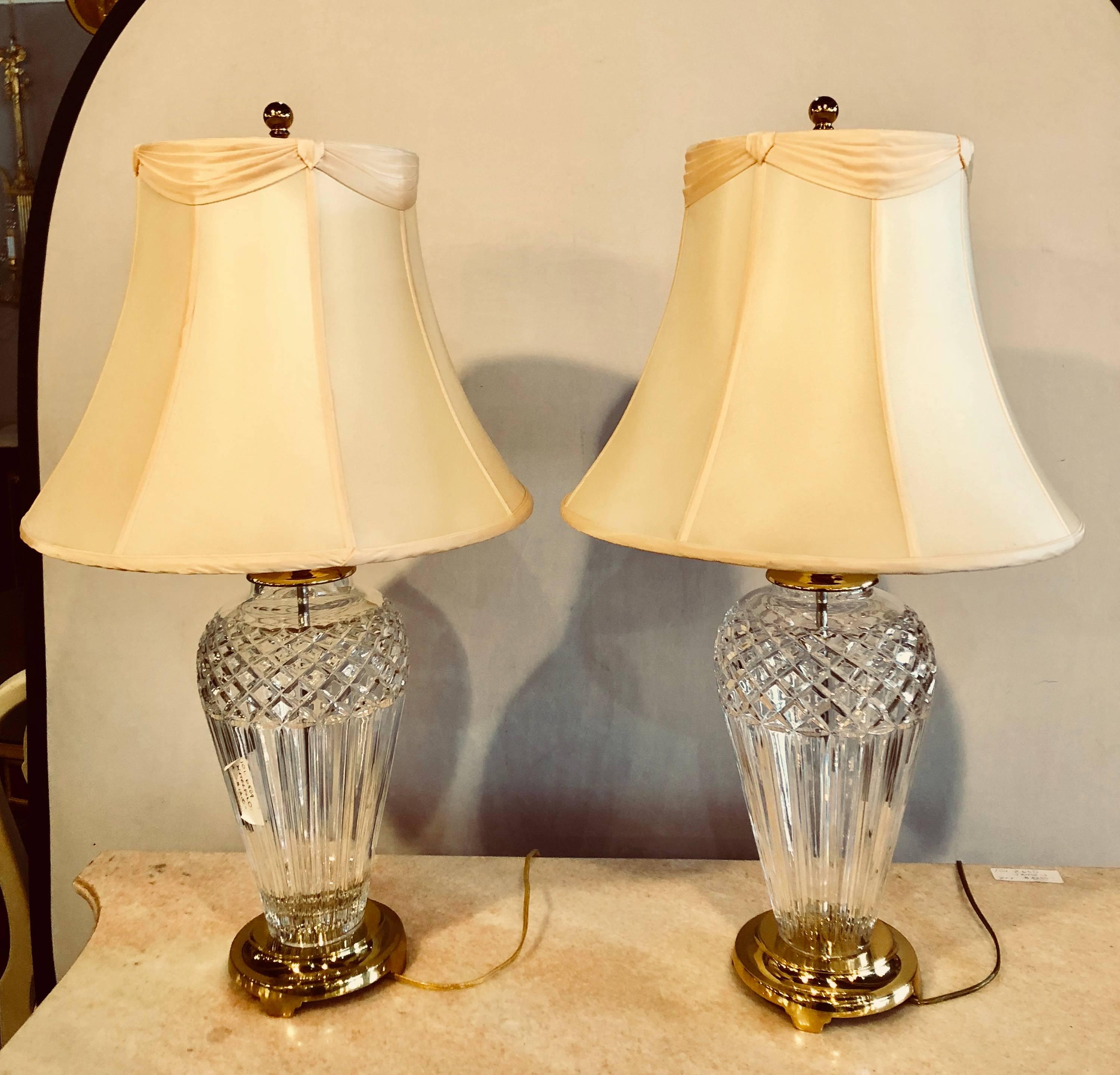 A pair of Waterford Crystal signed table lamps with stunning custom shades. Each standing on brass bases with brass caps and brass lampshade finials. Signed.