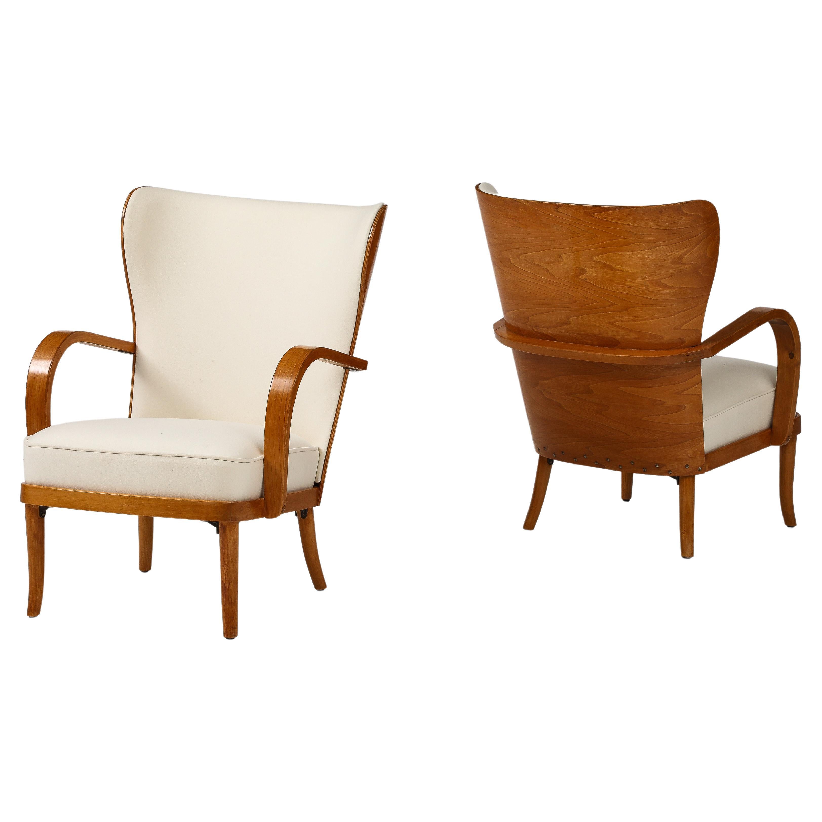 A pair of Finnish elmwood high back open-armchairs designed by Werner West, Circa 1930-40. Produced by Wilhelm Schaumannin, Vaneritehdas Oy, Jyväskylä, Finland. The high curved back with a form elmwood back, rolled arrested continuing behind the
