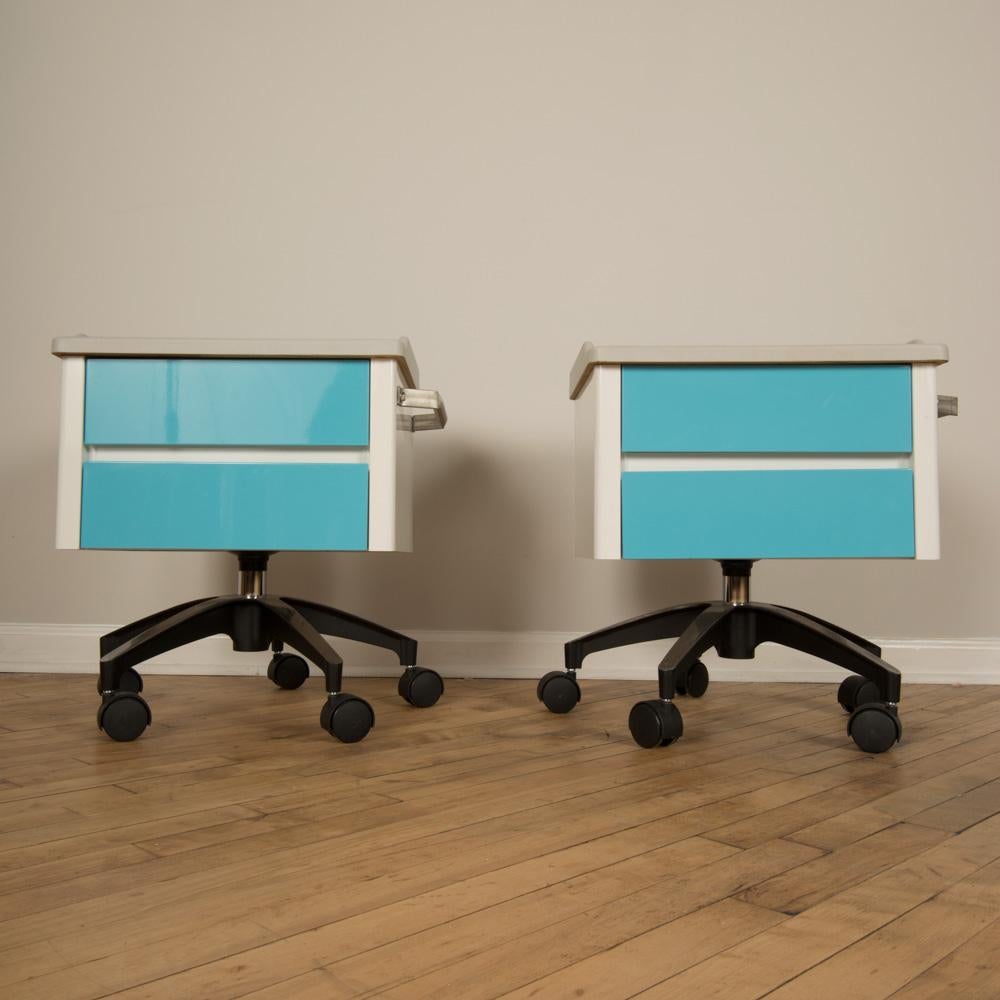 A pair of white and blue two drawers side cabinets on rolling base, 1970s.