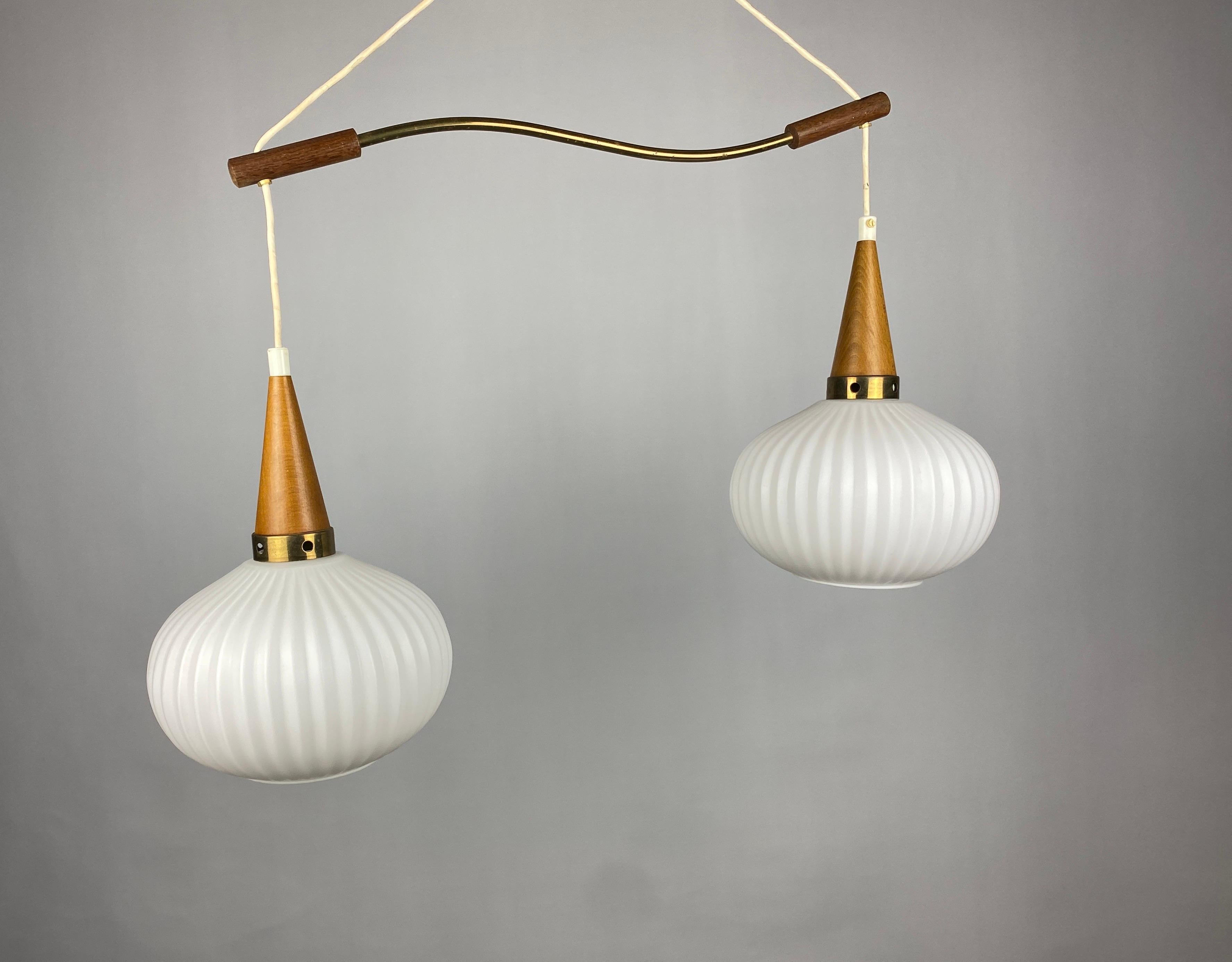 White opal frosted and ribbed pumpkin style oval glass pendant lights. Brass plated metal ring and accent. The two pendant lamps are held by a brass and wooden rod through which the cables run to the wooden ceiling cap.

Manufactured by Massive,