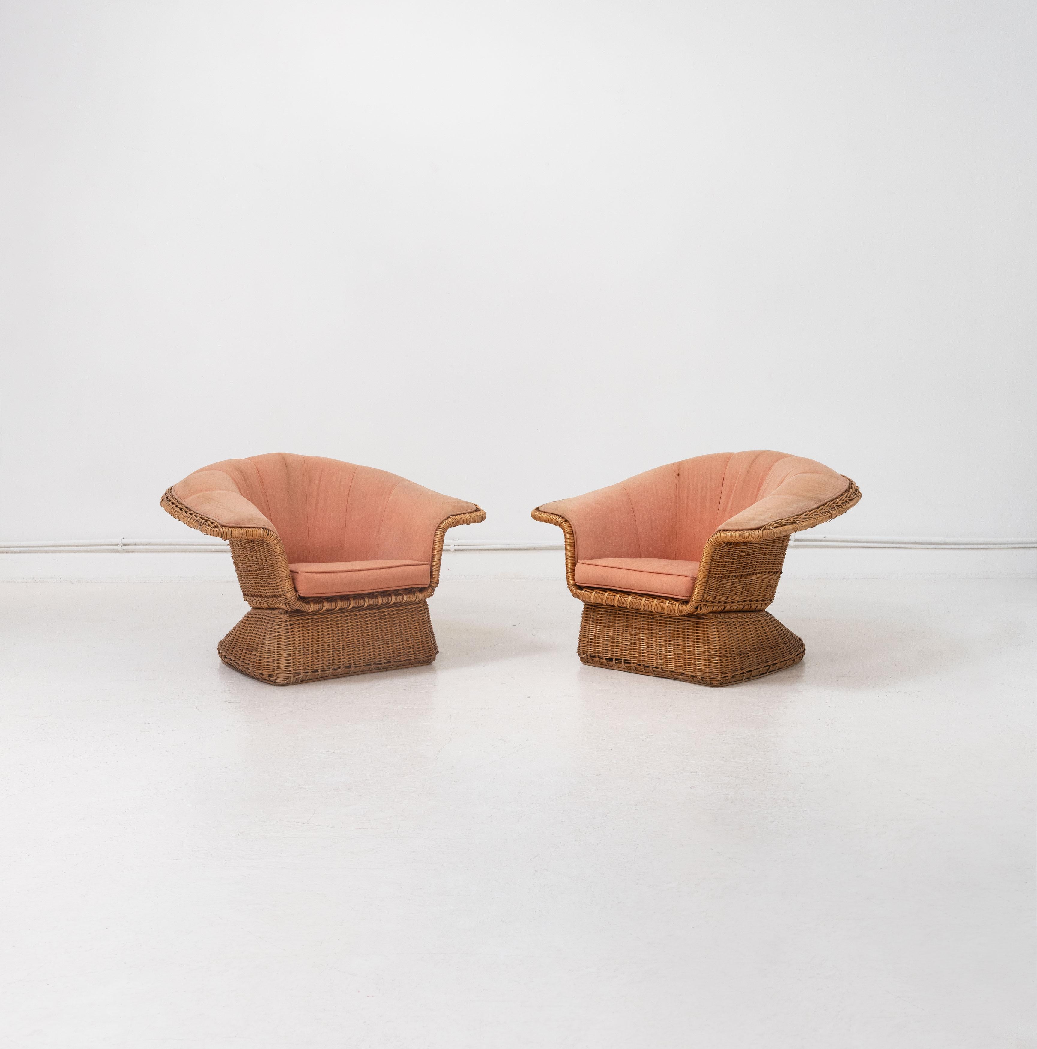 A pair of mid 20th Century wicker armchairs designed by Lyda Levi and produced by McGuire Company, San Francisco. Composed from rattan woven around a tubular metal frame and upholstered in a peach coloured fabric. 