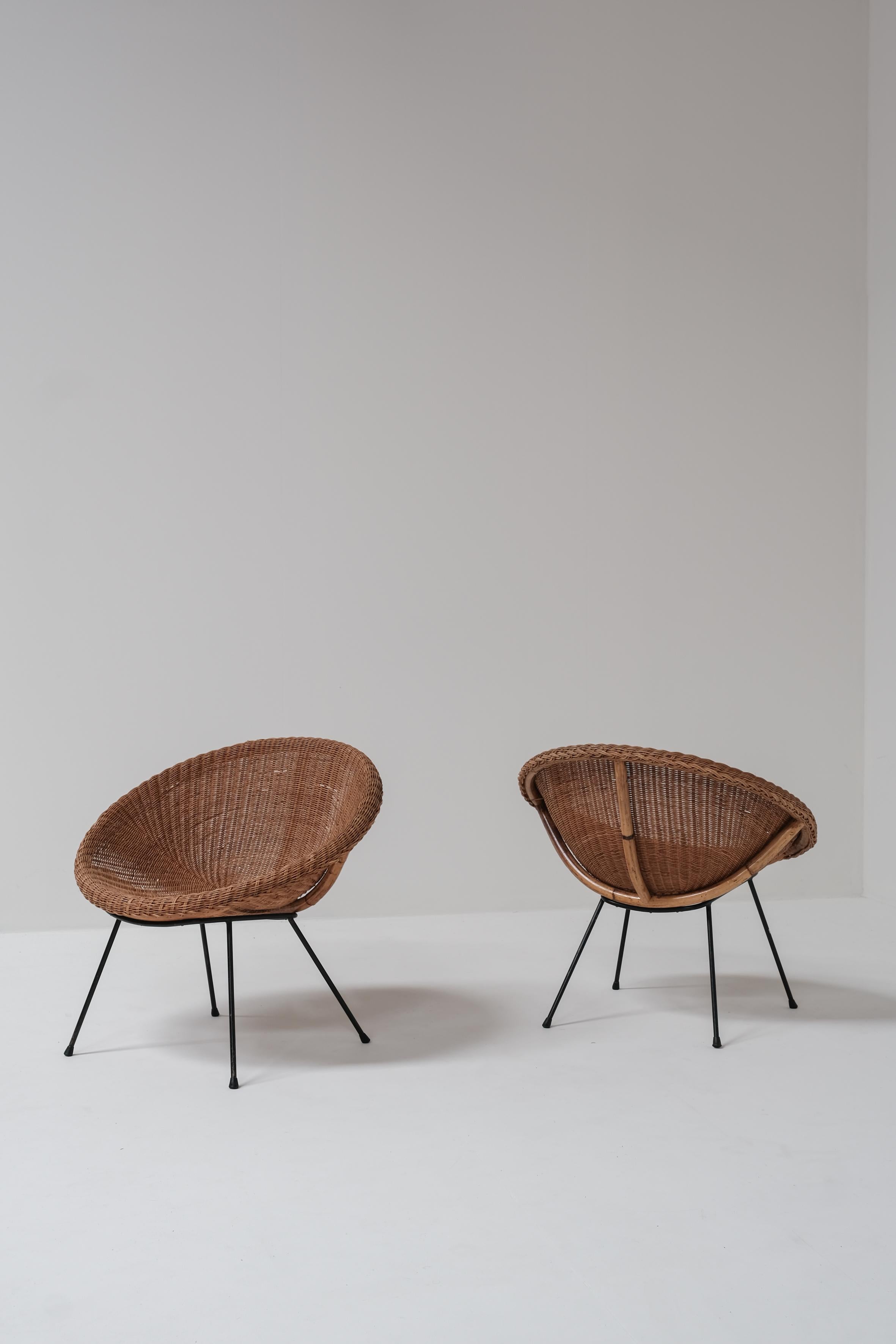 A pair of rattan bucket chairs, likely of French origin 1960, with an unknown designer.

They feature sturdy steel legs and a beautifully woven rattan seat base, combining durability with a natural aesthetic.

The chairs are in good overall