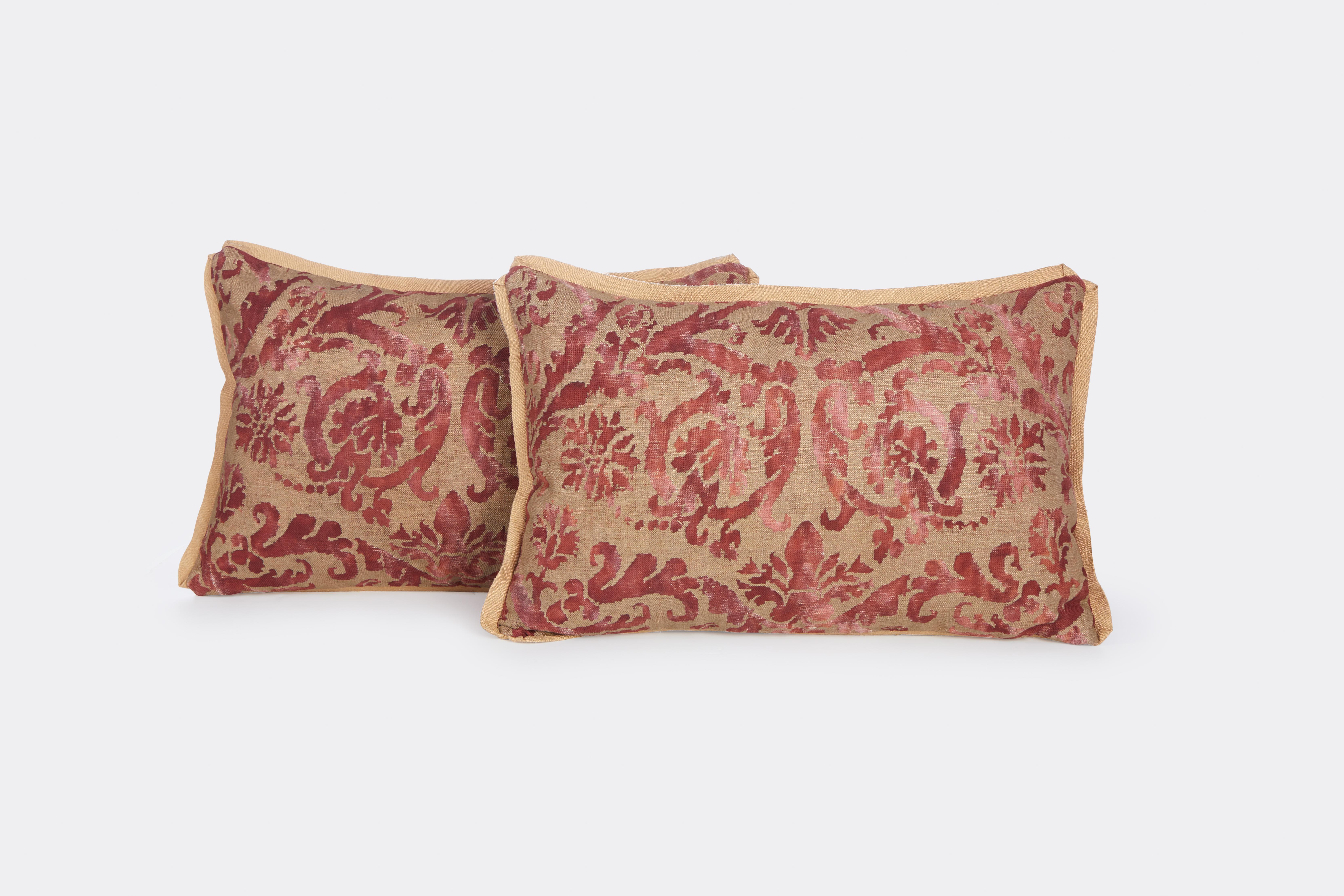 A pair of wine and gold damask patterned Fortuny lumbar cushions with gold silk bias edging and gold silk backs fabric c. 1940s.