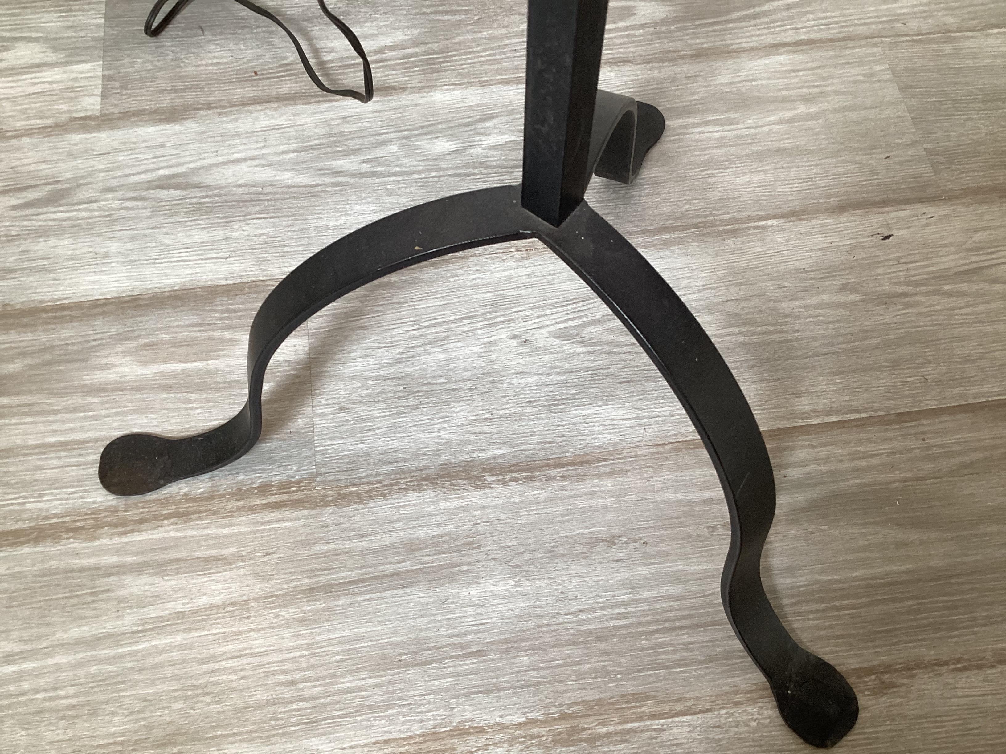 A Pair of adjustable Wrought Iron and Brass candlestick form floor lamps.  The adjustable arm with 2 candlestick style lights, with a center iron rod supported by three hand forges pedestal feet.  The measurement of the center pole is 59