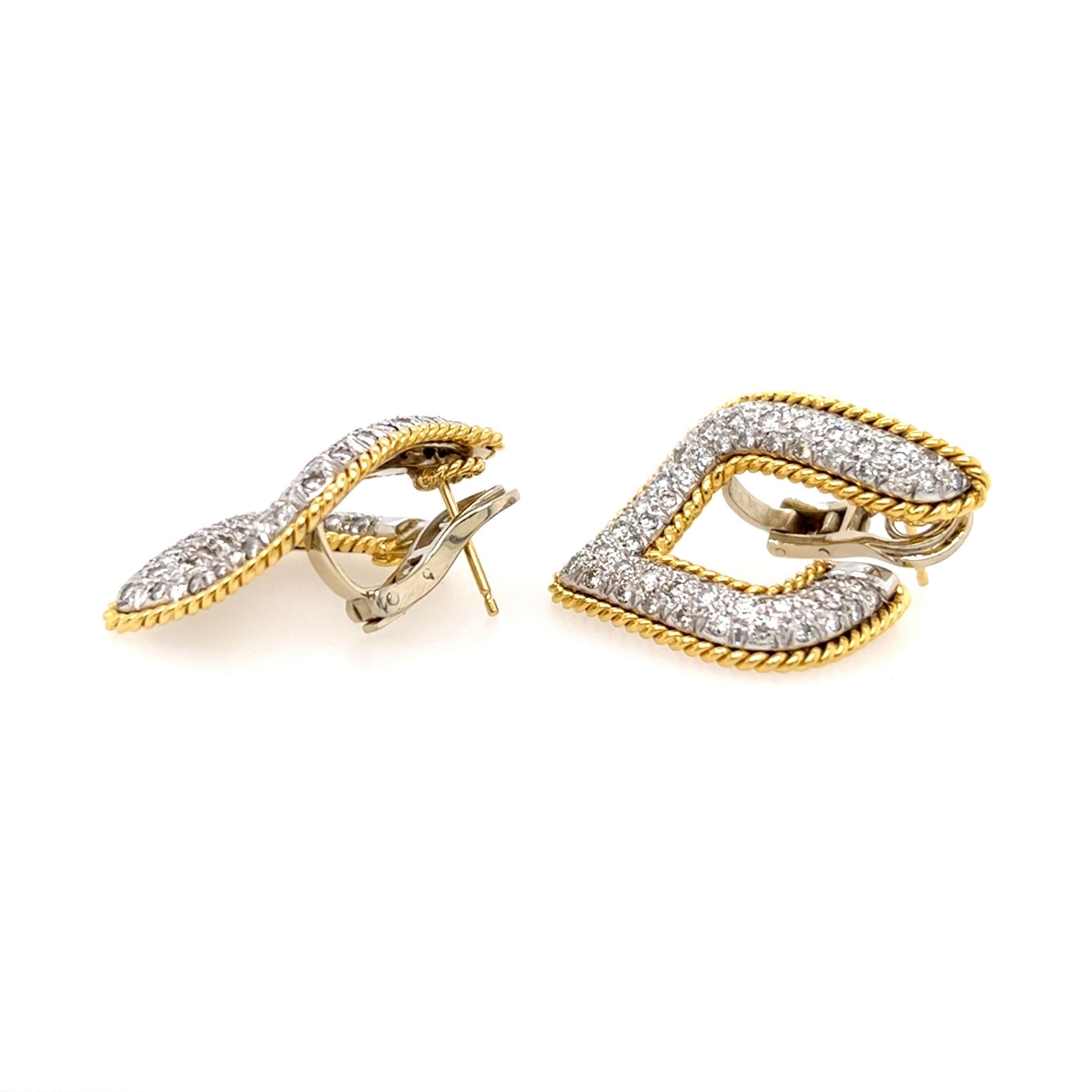 A pair of 18 karat yellow and white gold and diamond earrings.  Each earring designed as a slightly twisted open diamond shape pave set with approximately sixty seven (67) brilliant cut diamonds in white gold outlined with yellow gold ropework, the