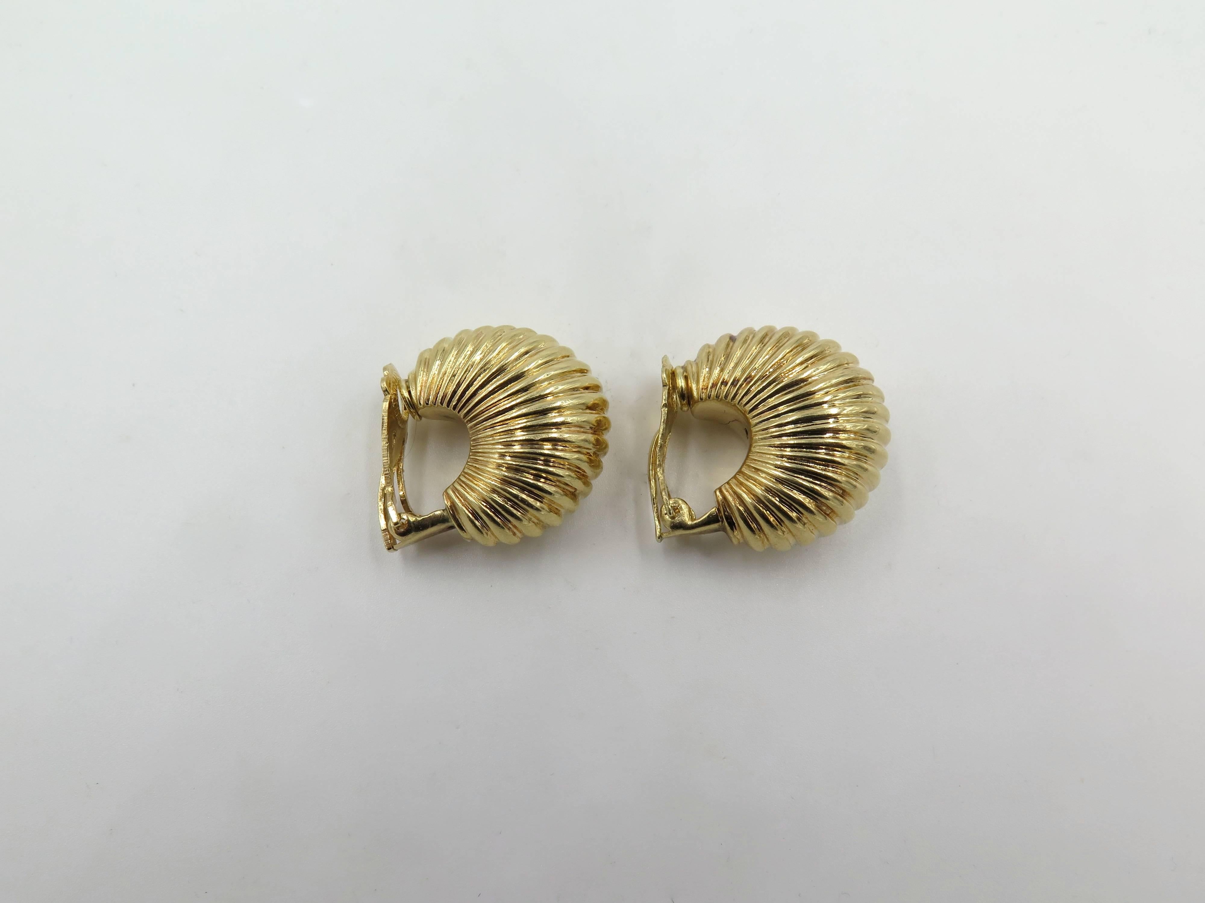 A pair of 14 karat yellow gold earrings. Circa 1950. Of fluted bombe half hoop design. Length is approximately 1 inch. Gross weight is approximately 23.7 grams. 