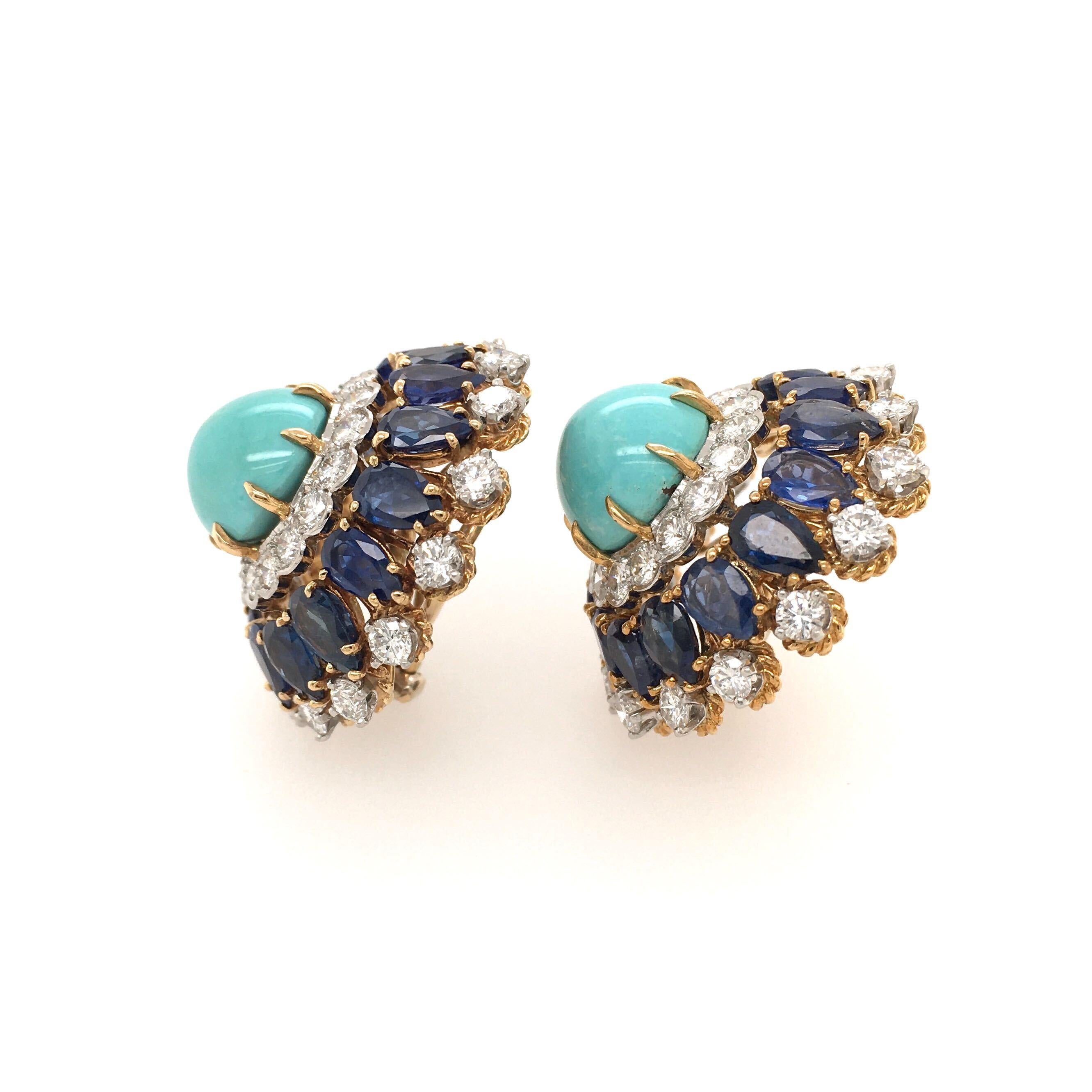 A pair of 18 karat yellow gold, turquoise, sapphire and diamond earrings. Set with a round cabochon turquoise, measuring approximately 12.5mm, within a circular cut diamond and pear shaped sapphire surround. Sixty two (62) diamonds weigh