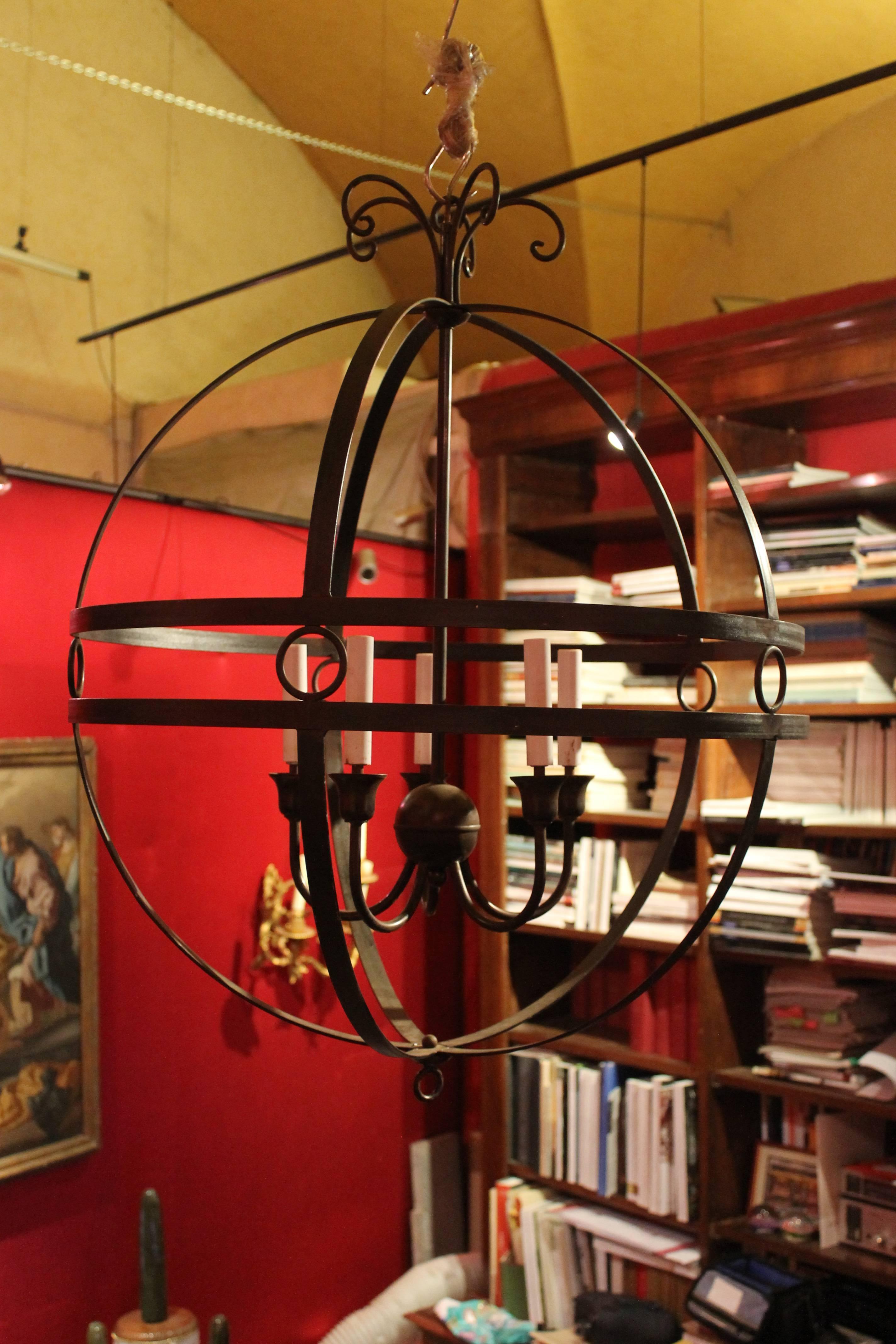 This beautiful pair of mid-century modern Italian dark brown hand-forged round iron chandelier have five candelabra base bulbs. All hand-forged globe body with decorative scrolling on the top and iron circles on banding. Two of these would make a