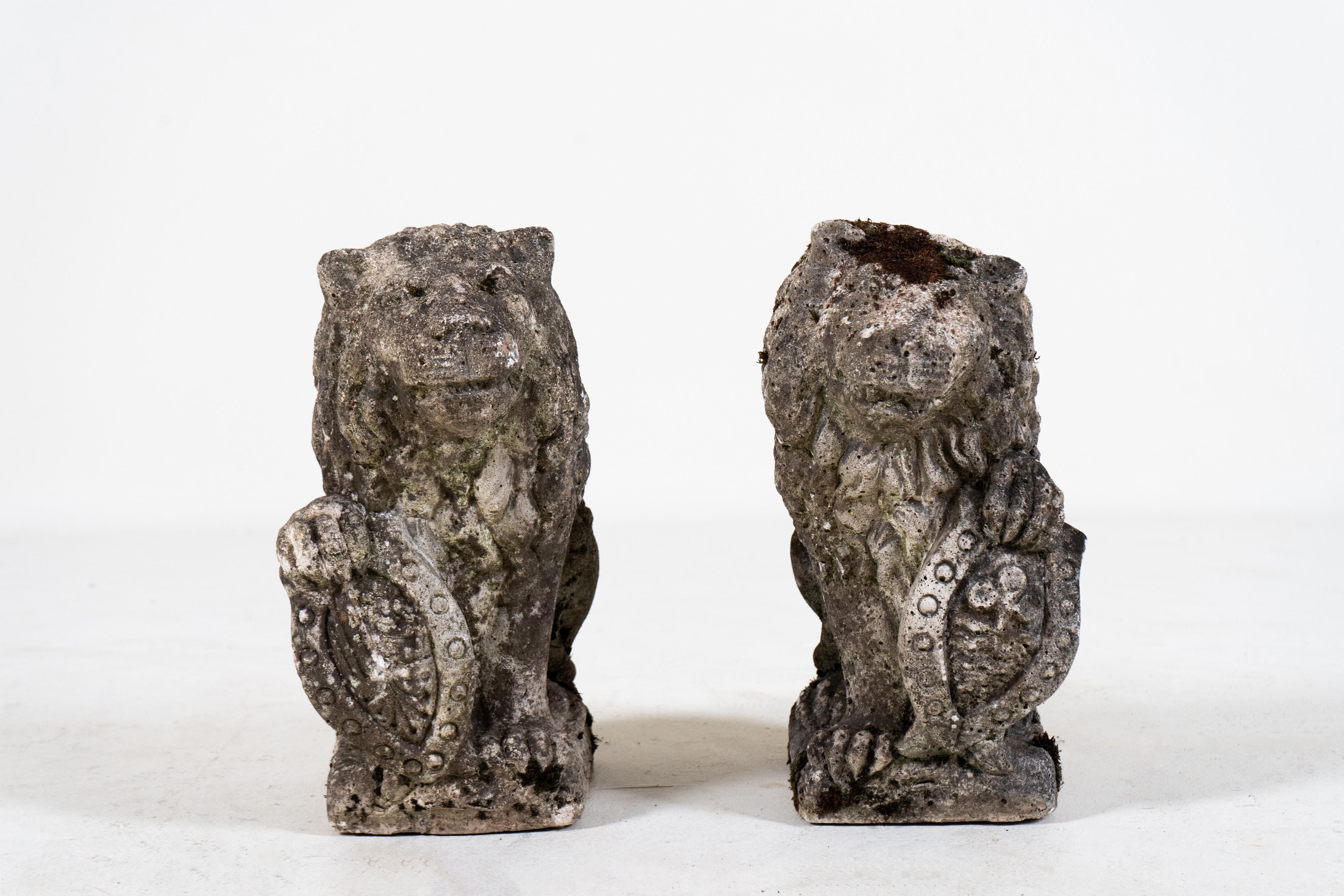 This antique pair of tufa limestone garden lions dates to the early 19th century and came from southern France or possibly, Italy. The lions are quite regal in appearance and hold heraldic shields with their paws. Their condition is good for their