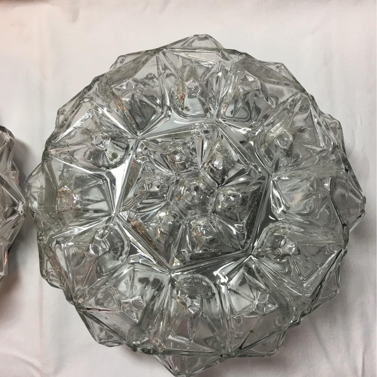 An elegant pair of round 1960s geometric glass structure flush mounts or sconces from Germany. The geometric structure of the glass helps create a fantastic lighting effect in the room. Each fixture requires one European E 26 / E27 Edison bulb, each