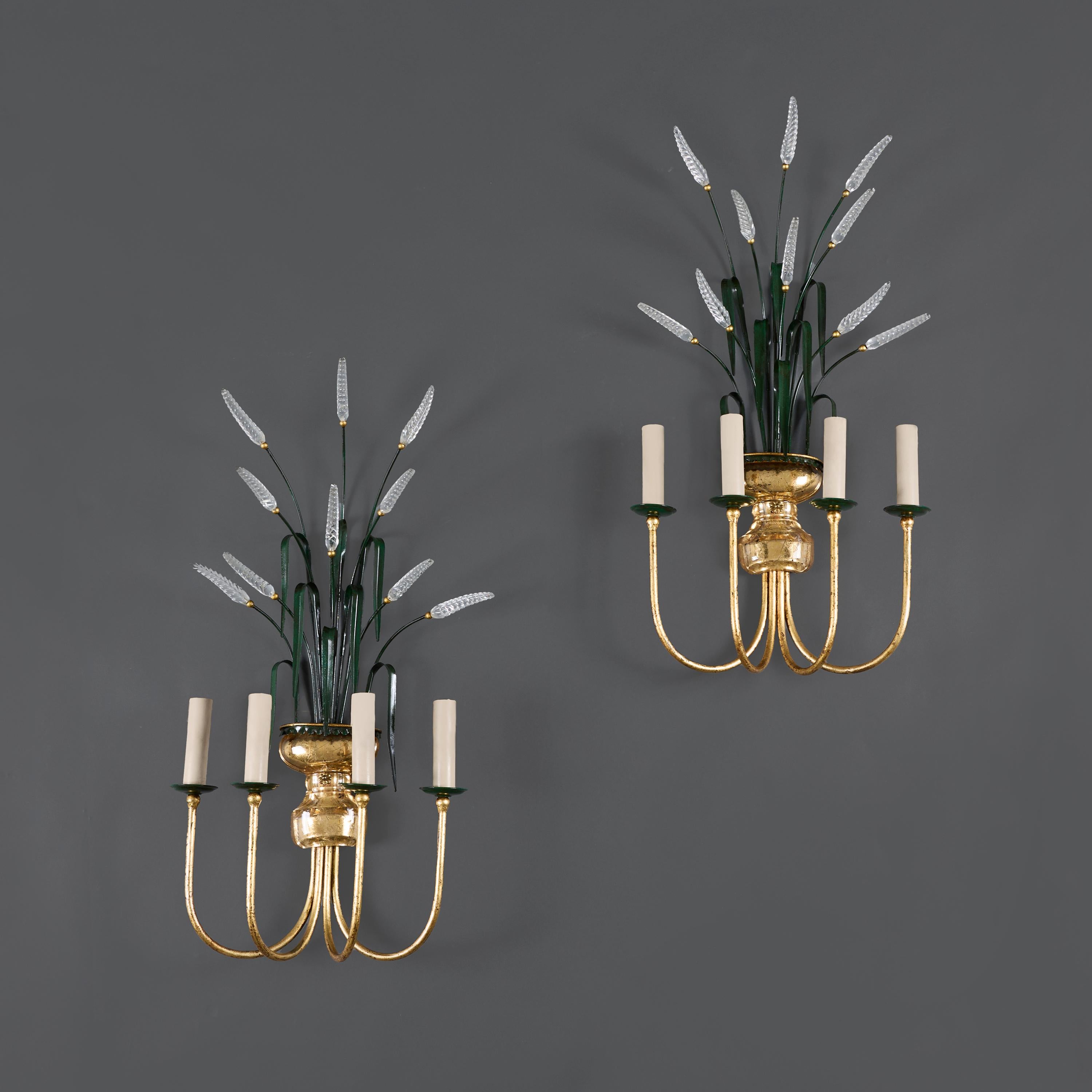 Francia, hacia 1940

Pareja de apliques de principios del siglo XX de Maison Bagues con cuatro brazos dorados, la urna central de cristal sostiene un ramillete de hojas de trigo tole pintadas de verde que terminan en espigas de cristal. 

Altura  