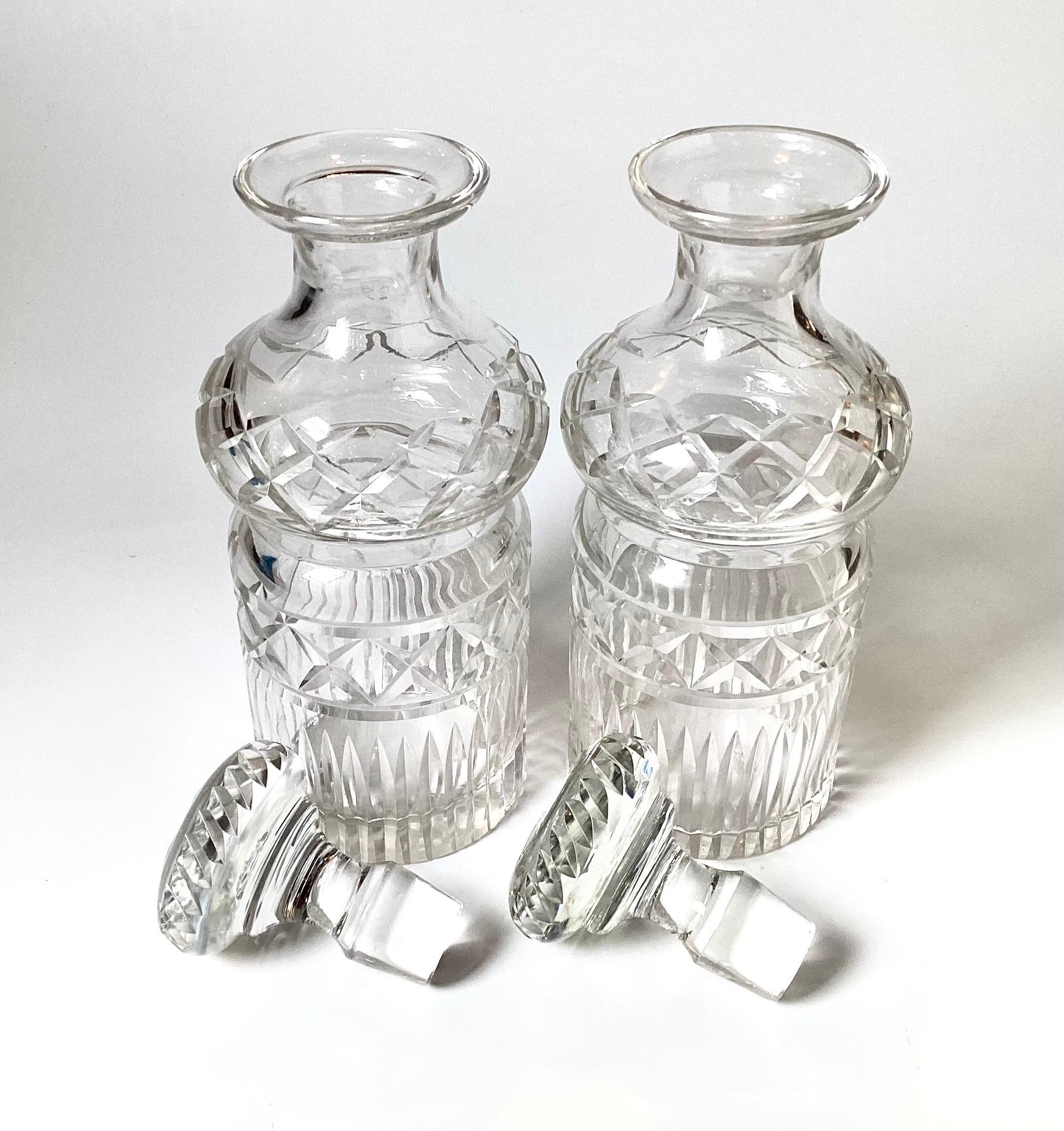 A Pair of European Cut glass spirit decanters with original stoppers. The round bottles with mushroom uppers with diamond pattern along with vertical cuts at the bottoms. Measures: 11 high, 4.5 inches in dimaeter.