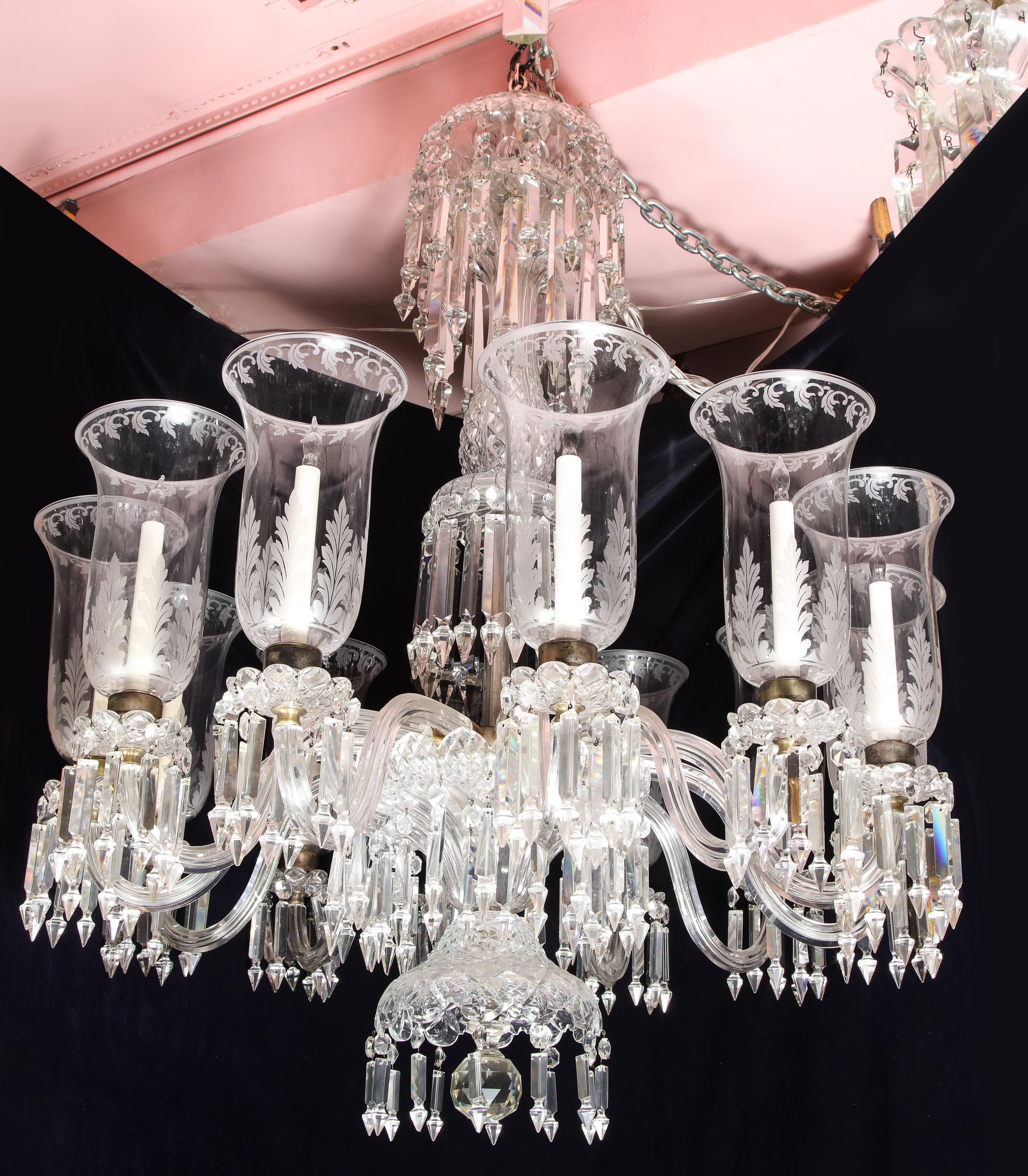 A palatial and large antique French Louis XVI cut crystal multi light chandelier of exceptional craftsmanship embellished with hand handcut crystal arms, cut crystal prisms and further adorned with superb hand acid etched hurricane glass globes
