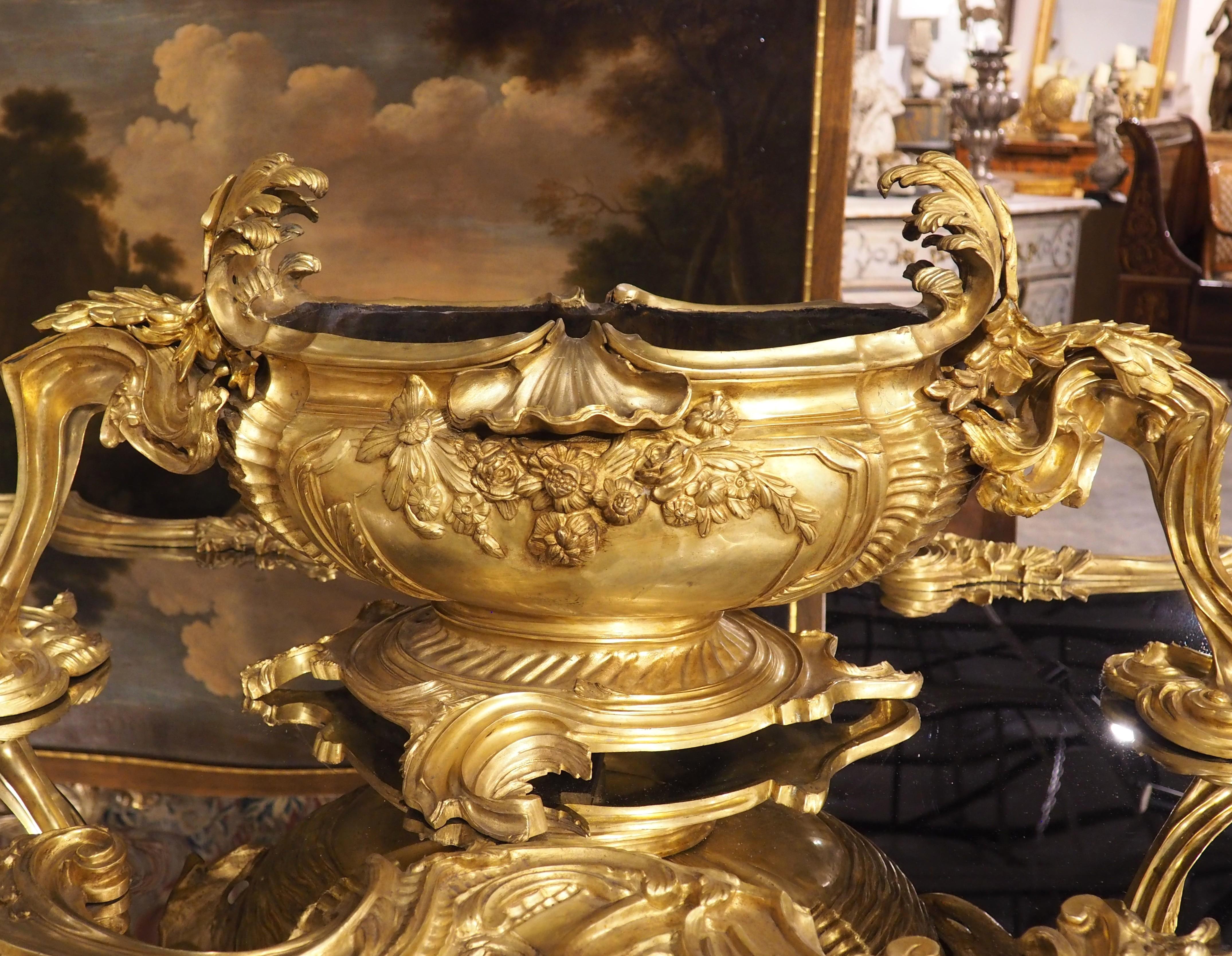 Mesurant 74 ½ pouces de long, ce surtout de table palatial en bronze doré avec miroir ferait une merveilleuse pièce maîtresse pour une table de salle à manger. Son imposante jardinière s'élève à plus de 15 cm au-dessus du miroir, soutenue par des