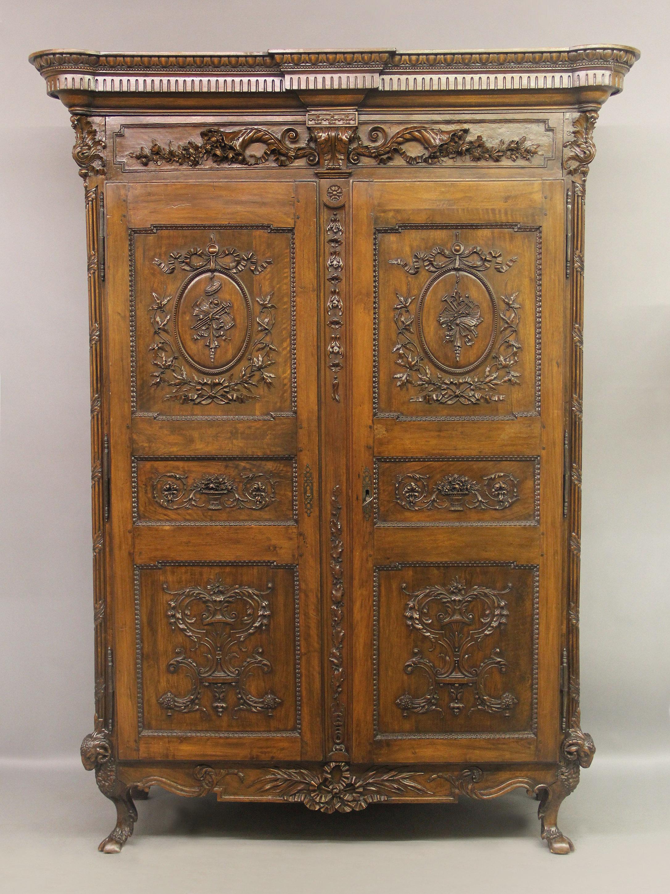 A palatial and very fine late 18th century Louis XVI hand carved walnut and mahogany armoire

The country French cabinet with a rectangular cornice above a pair of large doors raised on short cabriole legs surmounted by ram's heads and hooves. The