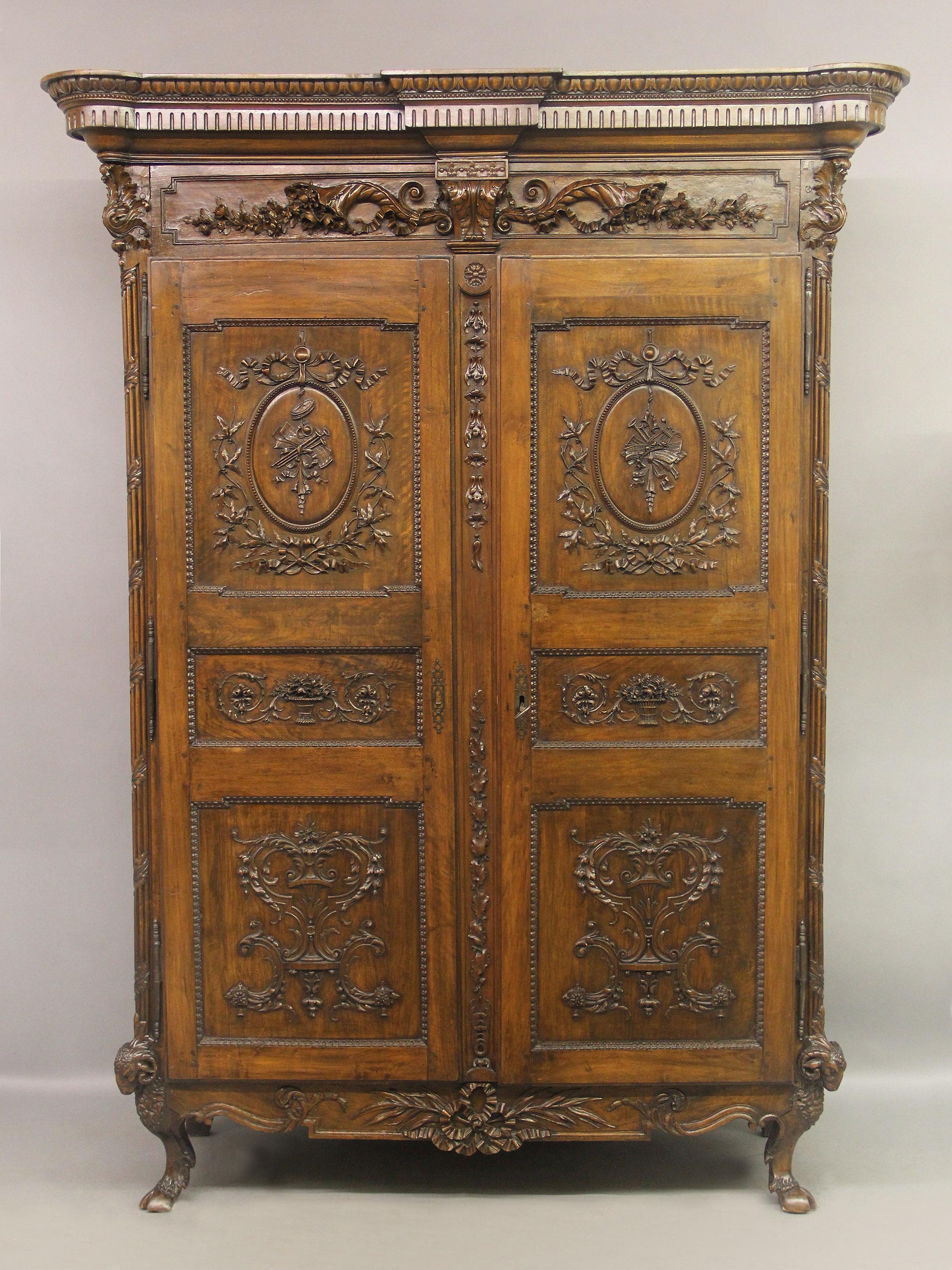 A palatial and very fine late 18th century Louis XVI hand carved walnut and mahogany armoire

The country French cabinet with a rectangular cornice above a pair of large doors raised on short cabriole legs surmounted by ram's heads and hooves. The