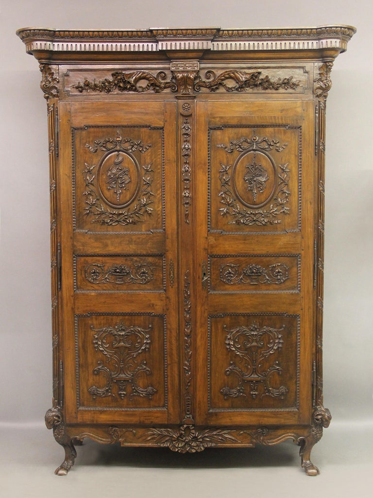 A palatial and very fine late 18th century Louis XVI hand carved walnut and mahogany armoire

The country French cabinet with a rectangular cornice above a pair of large doors raised on short cabriole legs surmounted by ram's heads and hooves. The
